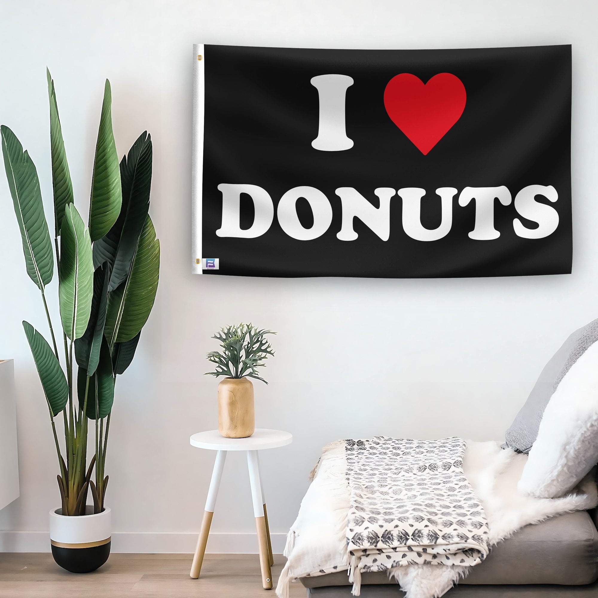 In a home setting, a flag with the saying "I Love Donuts" is mounted on a white wall by a side table.