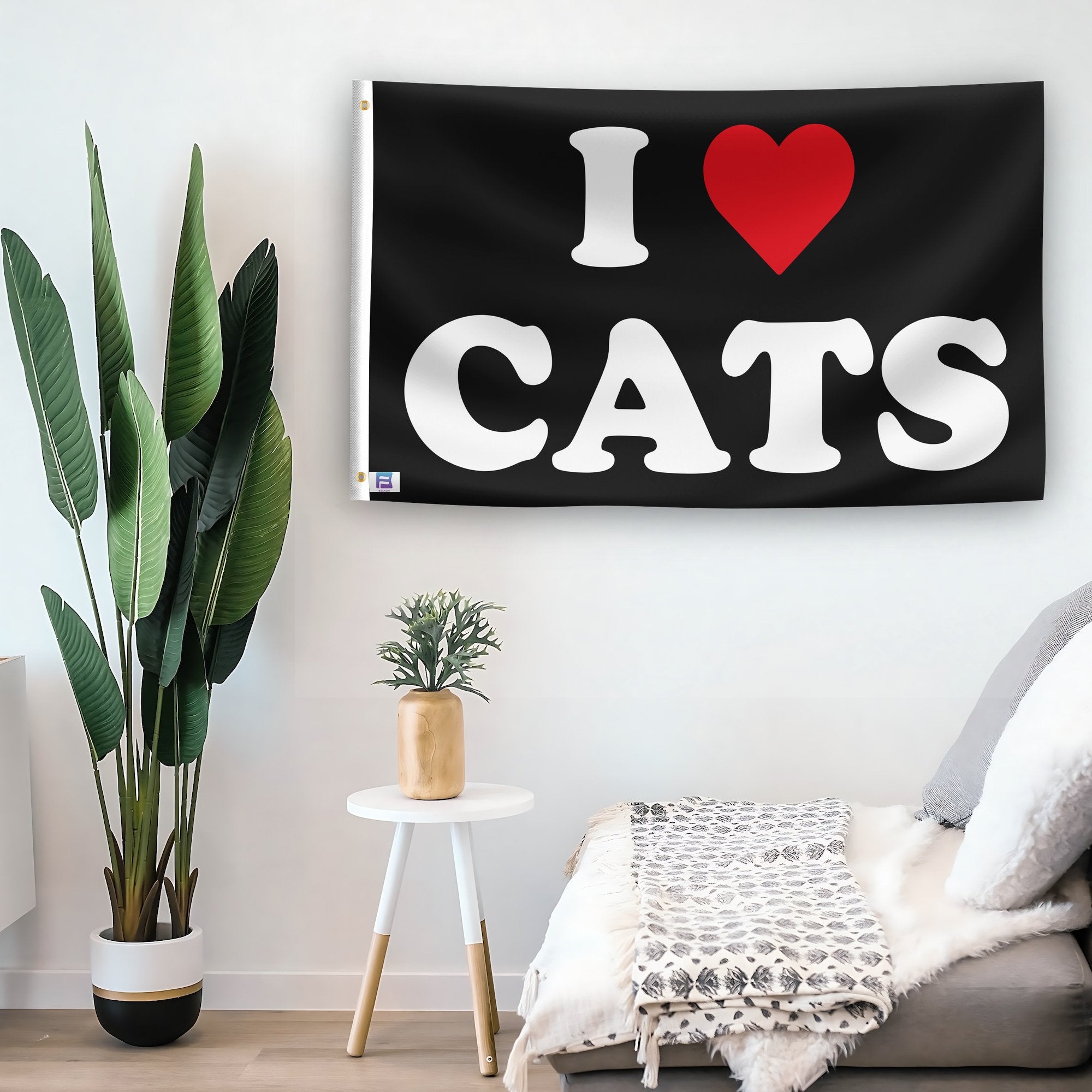 In a home setting, a flag with the saying "I Love Cats" is mounted on a white wall by a side table.