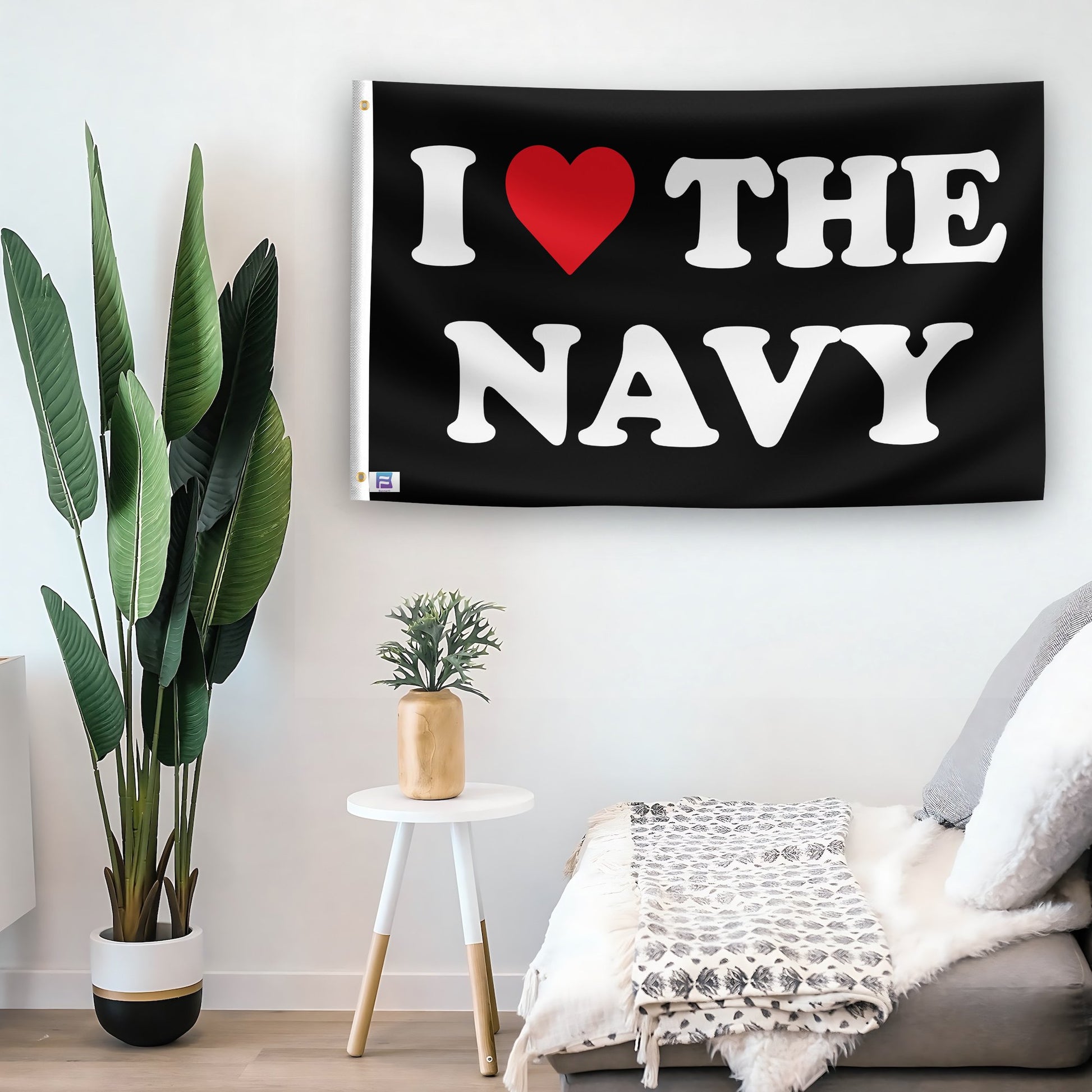 In a home setting, a flag with the saying "I Love The Navy" is mounted on a white wall by a side table.