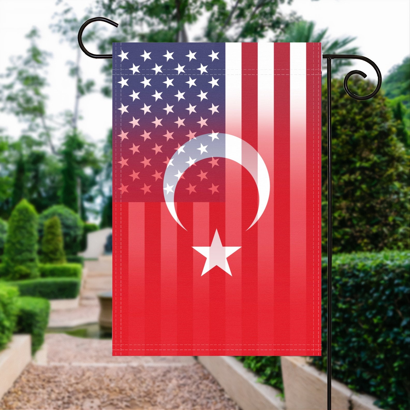 A garden flag with the Turkish American flag design seamlessly blended with the American flag, displayed in a garden.