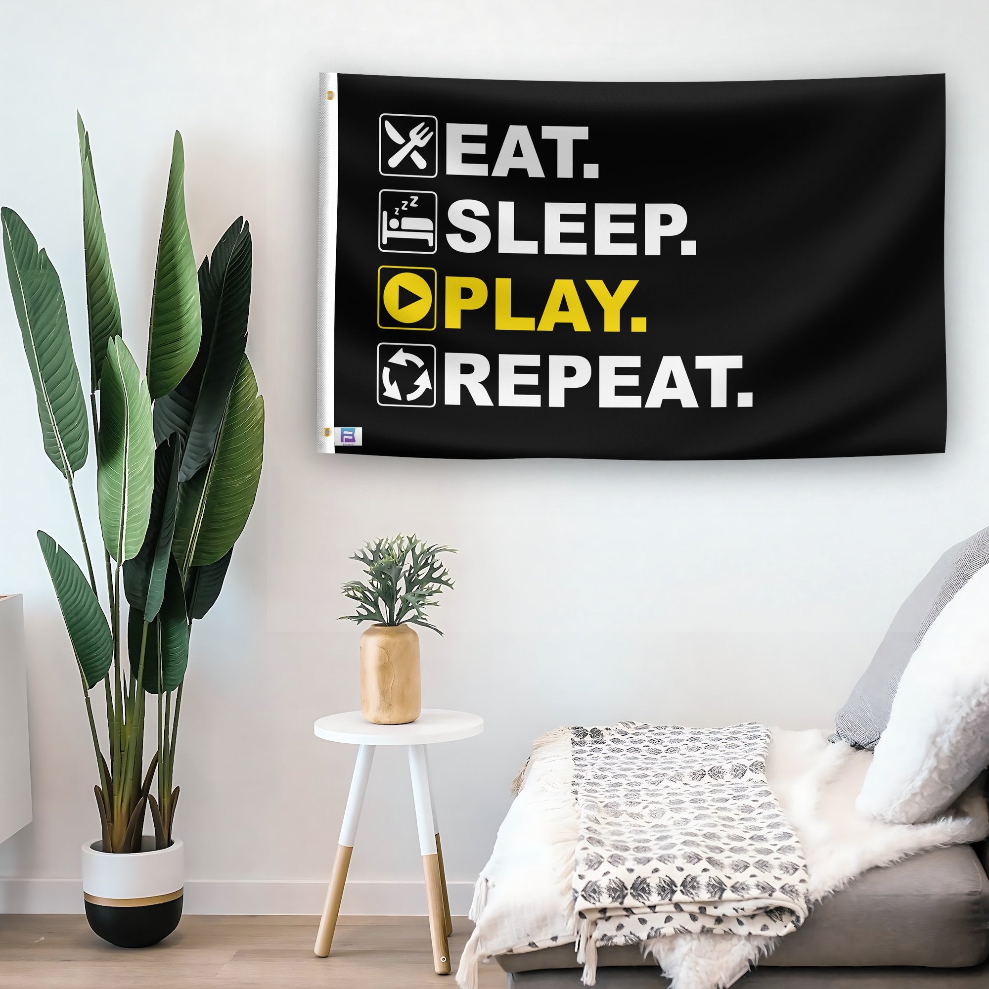 In a home setting, a flag with the saying "Eat Sleep Play Repeat" is mounted on a white wall by a side table.