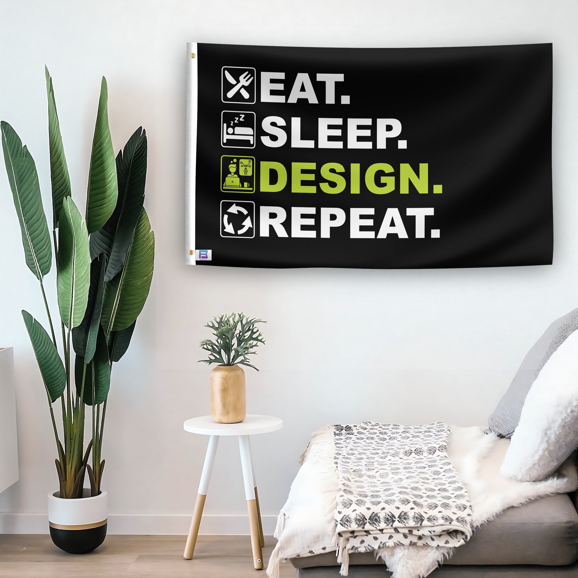 In a home setting, a flag with the saying "Eat Sleep Design Repeat" is mounted on a white wall by a side table.