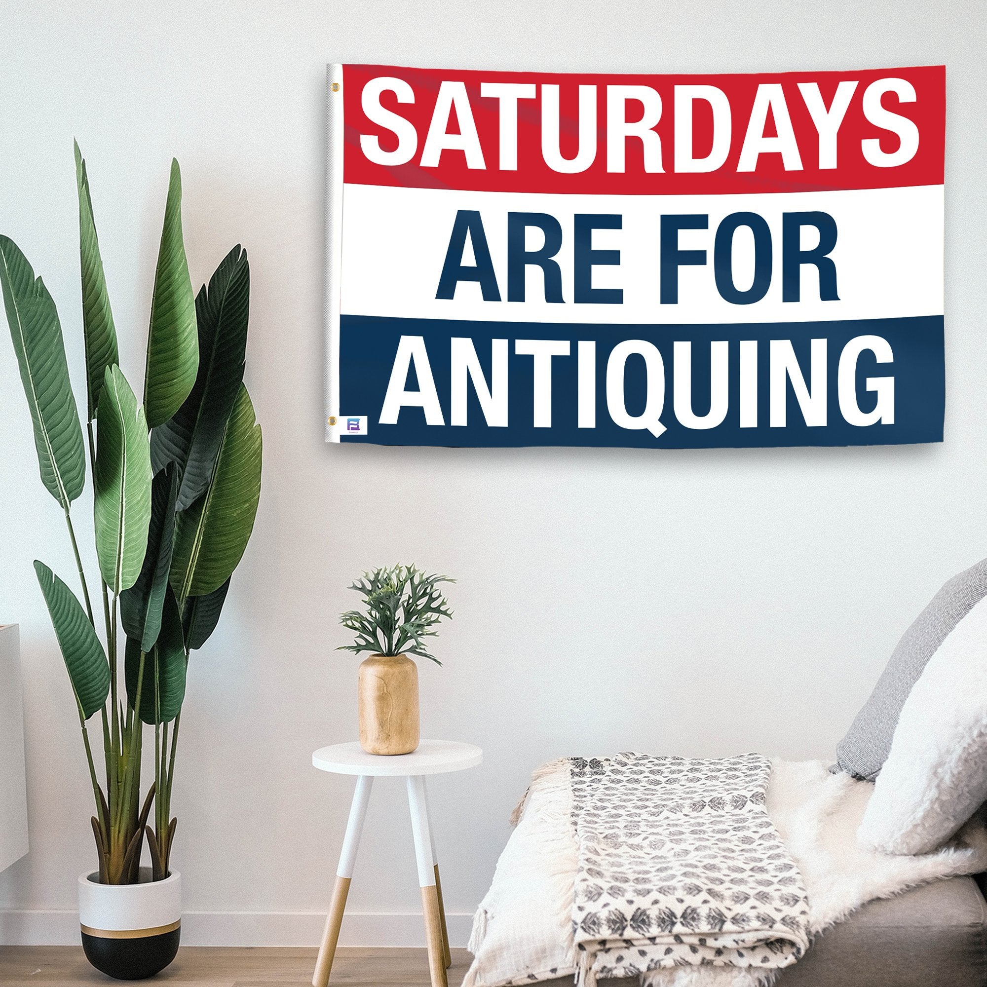 In a home setting, a flag with the saying "https://www.dropbox.com/scl/fi/23uauu1m6pk5kqyrshwg6/saturdays-are-for-antiquing_room.png?rlkey=tg1jao377ymo5mv2ojrk4myq8&raw=1" is mounted on a white wall by a side table.