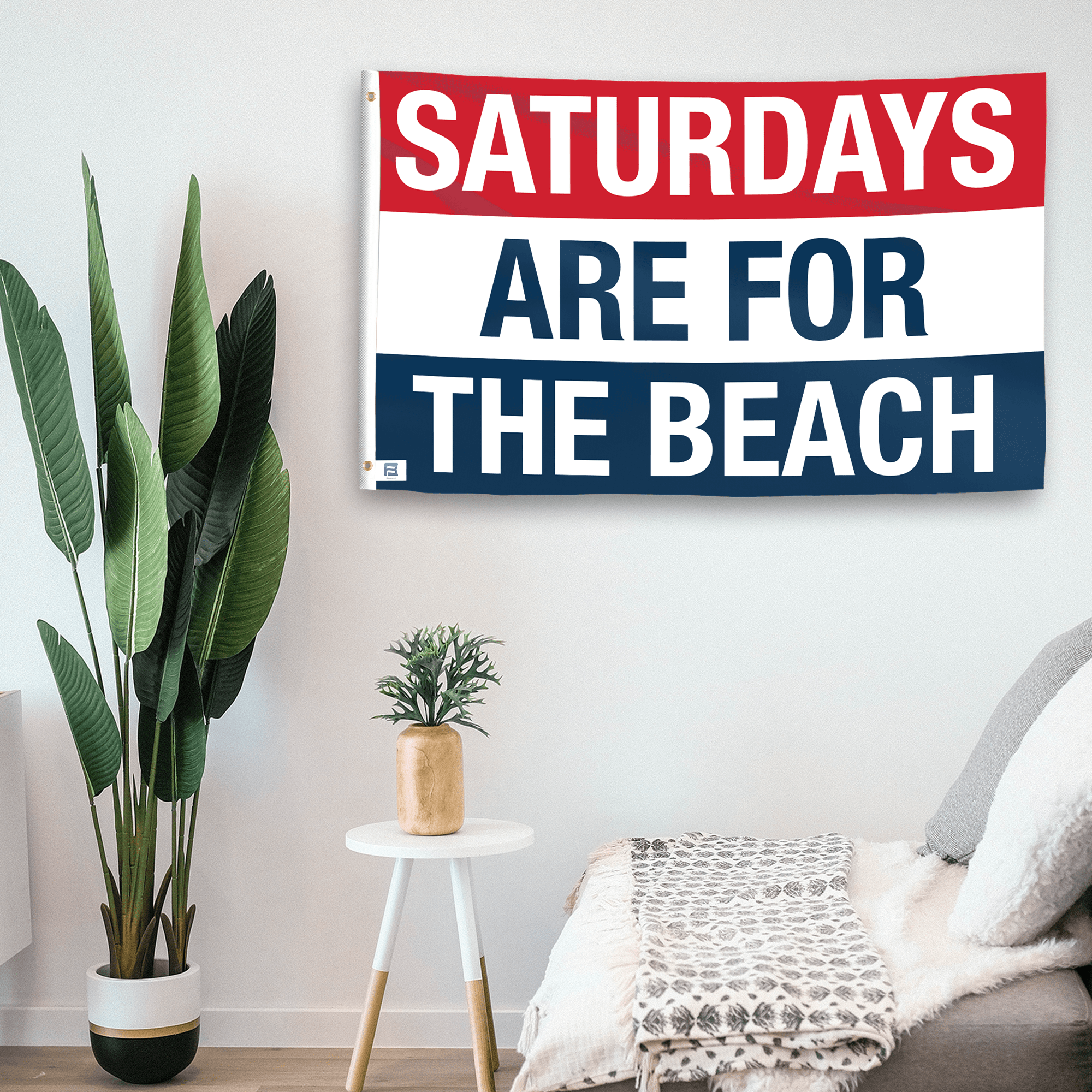 In a home setting, a flag with the saying "https://www.dropbox.com/scl/fi/8n65lo8bf25u191vojvs8/saturdays-are-for-the-beach_room.png?rlkey=2efedj9zw42w1vzyx4ip44fcr&raw=1" is mounted on a white wall by a side table.