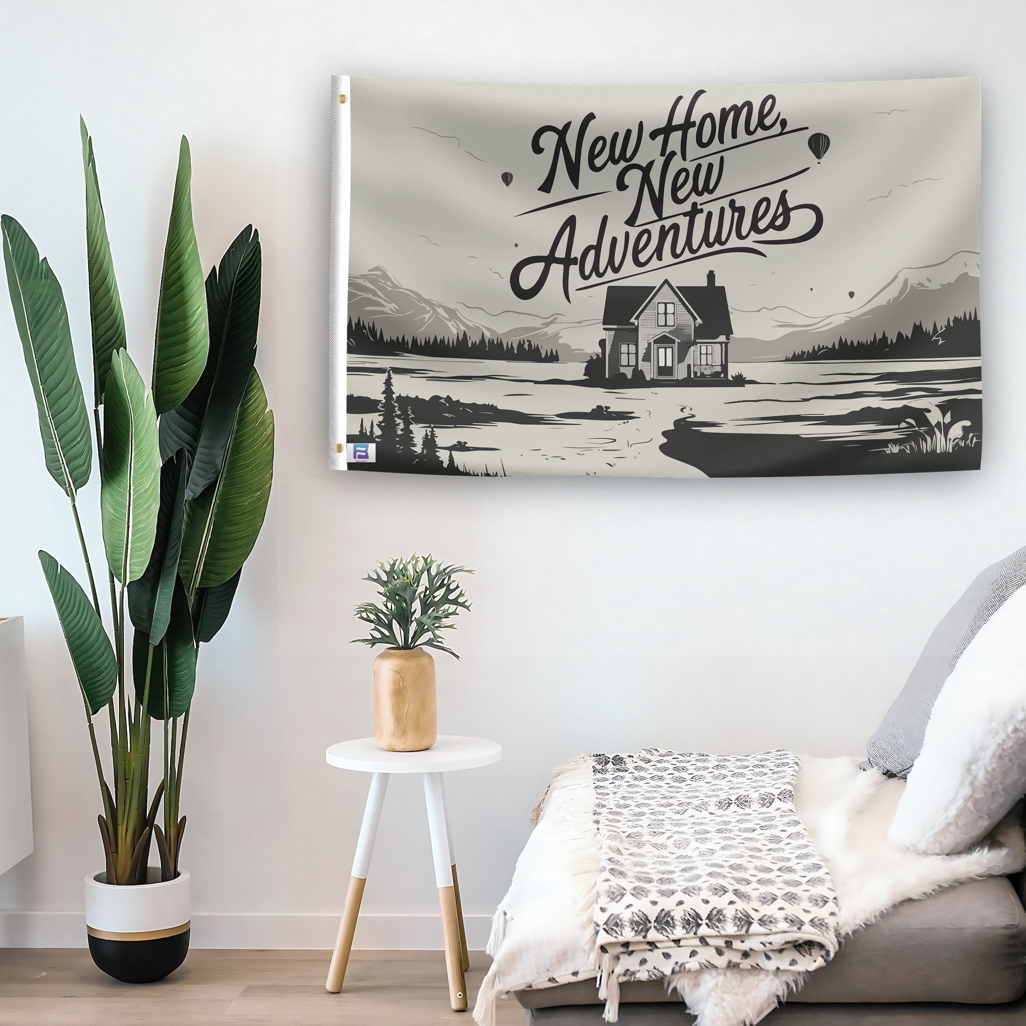 In a home setting, a flag with the saying "New Home New Adventures" is mounted on a white wall by a side table.