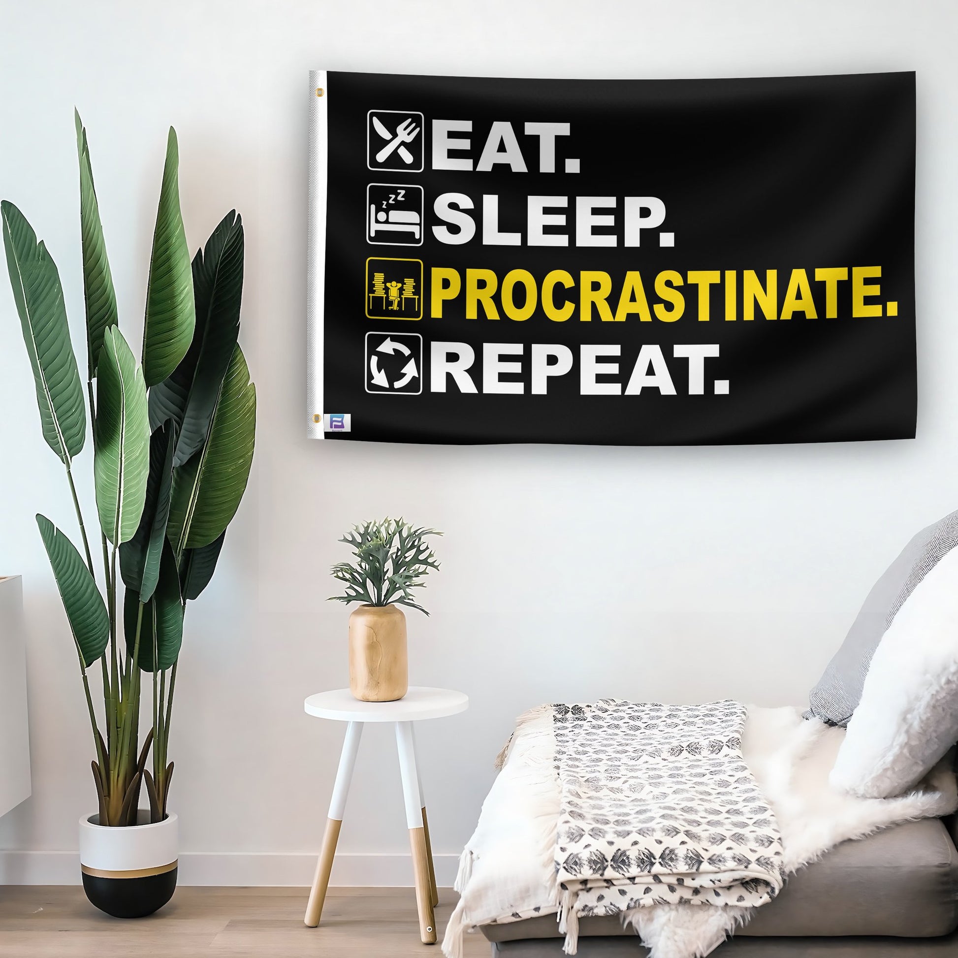 In a home setting, a flag with the saying "Eat Sleep Procrastinate Repeat" is mounted on a white wall by a side table.