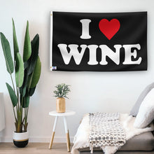 Load image into Gallery viewer, In a home setting, a flag with the saying &quot;I Love Wine&quot; is mounted on a white wall by a side table.
