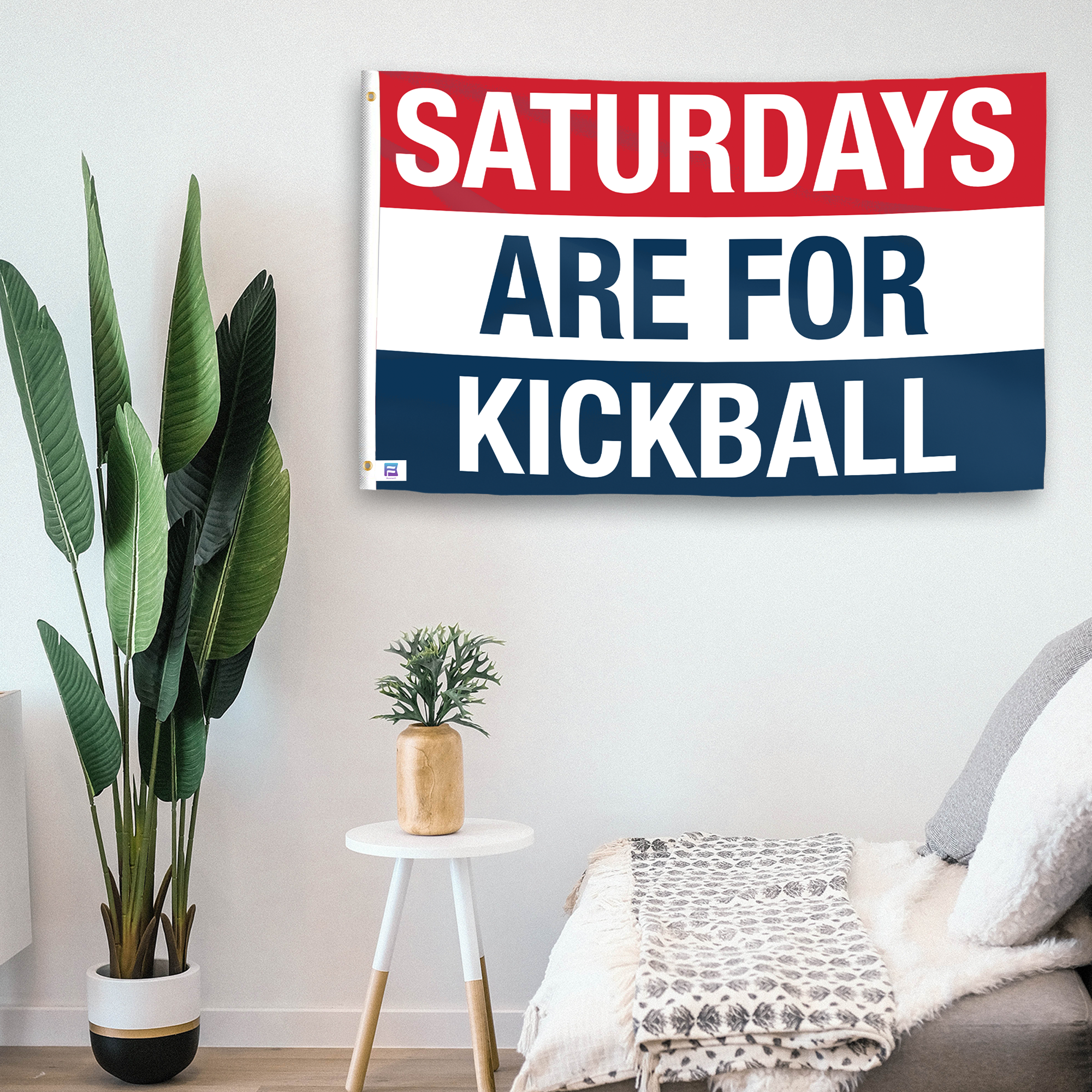 In a home setting, a flag with the saying "https://www.dropbox.com/scl/fi/zn638yzan5ucu8gmdlnll/saturdays-are-for-kickball_room.png?rlkey=giavny31sll3zd53il6wrq0b5&raw=1" is mounted on a white wall by a side table.