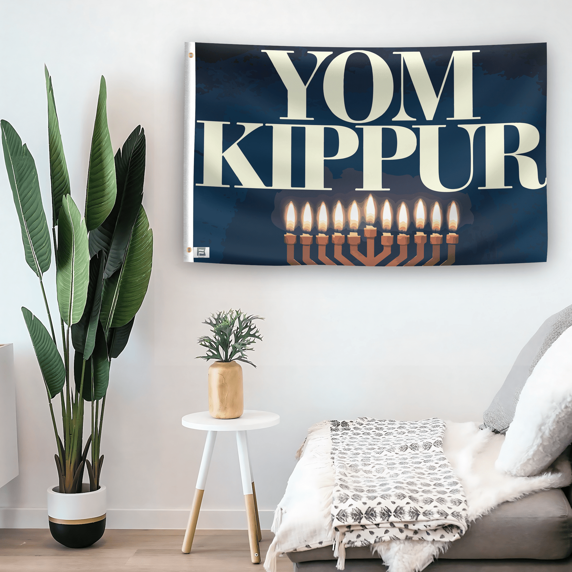 In a home setting, a flag with the saying "YOM Kippur" is mounted on a white wall by a side table.