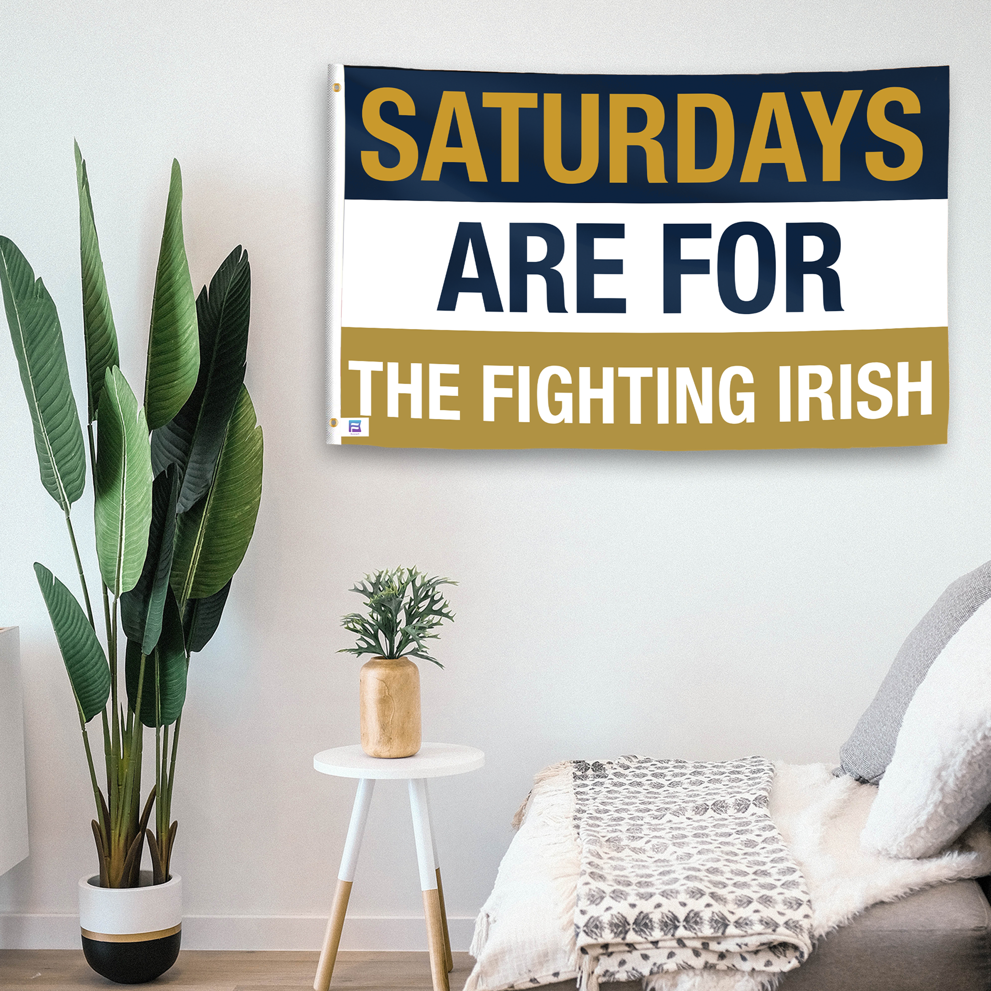 In a home setting, a flag with the saying "Saturdays Are for the Fighting Irish" is mounted on a white wall by a side table.