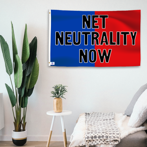 In a home setting, a blue and red flag with a political slogan is mounted on a white wall by a side table.