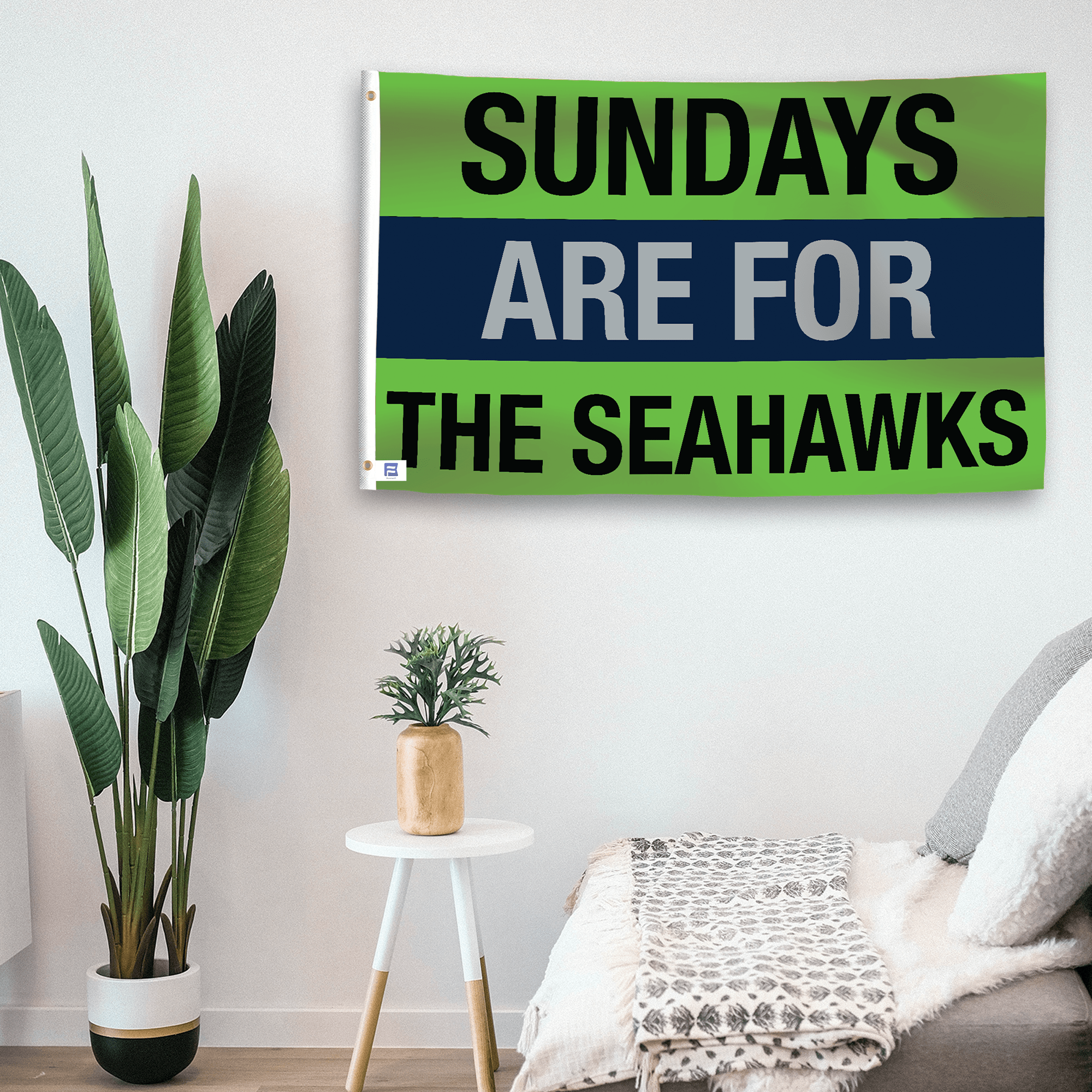 In a home setting, a flag with the saying "https://www.dropbox.com/scl/fi/4eqab6mrwroz163xtu6a2/sundays-are-for-the-seahawks_room.png?rlkey=uismfkyphxs1plfxi6g5s5k1v&raw=1" is mounted on a white wall by a side table.