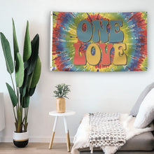 Load image into Gallery viewer, In a home setting, a flag with the saying &quot;One Love&quot; is mounted on a white wall by a side table.
