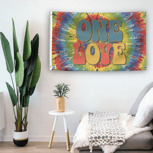 In a home setting, a flag with the saying "One Love" is mounted on a white wall by a side table.