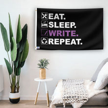 Load image into Gallery viewer, In a home setting, a flag with the saying &quot;Eat Sleep Write Repeat&quot; is mounted on a white wall by a side table.
