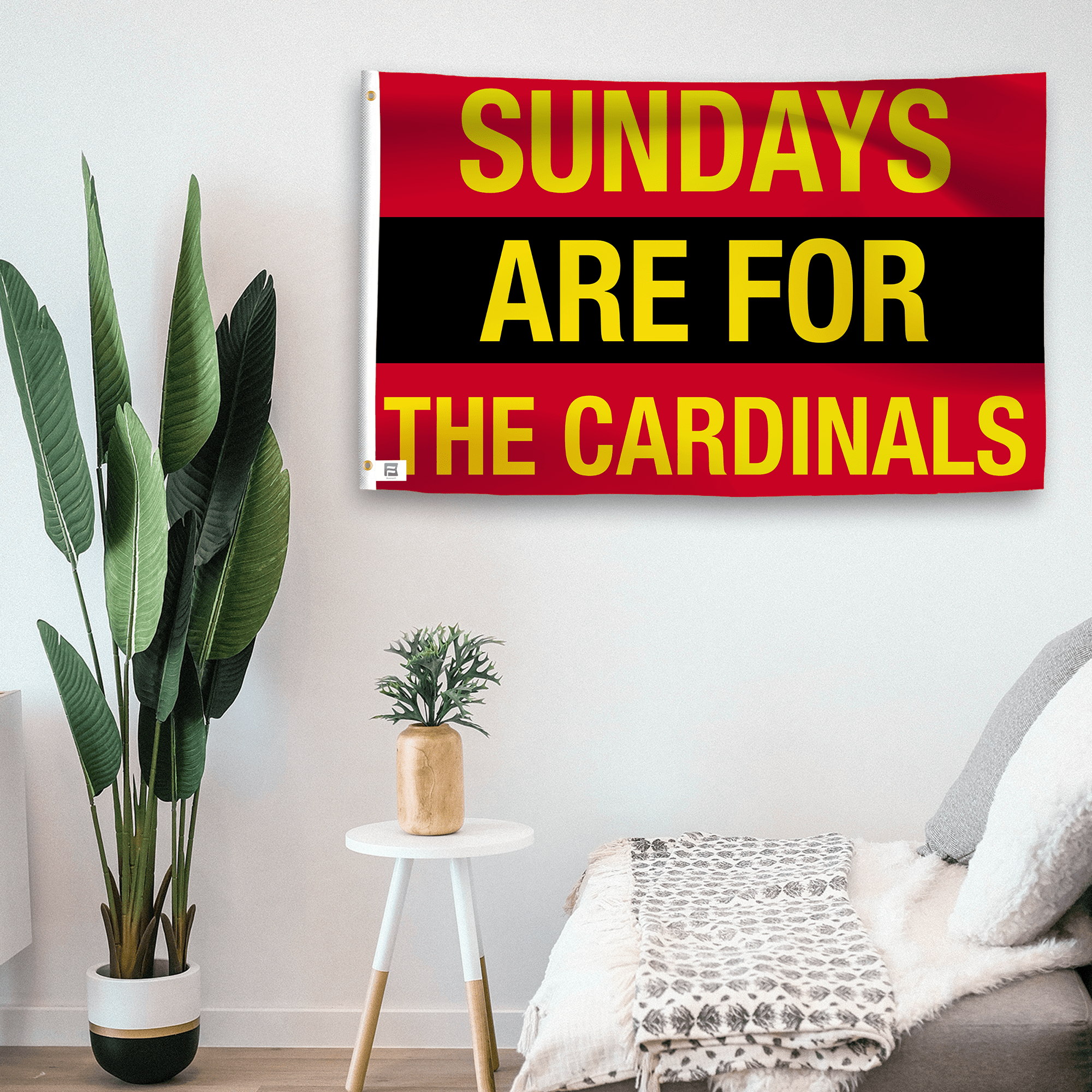 In a home setting, a flag with the saying "https://www.dropbox.com/scl/fi/n2z7arda01bothzd7wwrx/sundays-are-for-the-cardinals_room.png?rlkey=3dgkl9lvzo14imidxsuwyqvdk&raw=1" is mounted on a white wall by a side table.