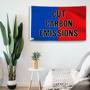 In a home setting, a blue and red flag with a political slogan is mounted on a white wall by a side table.