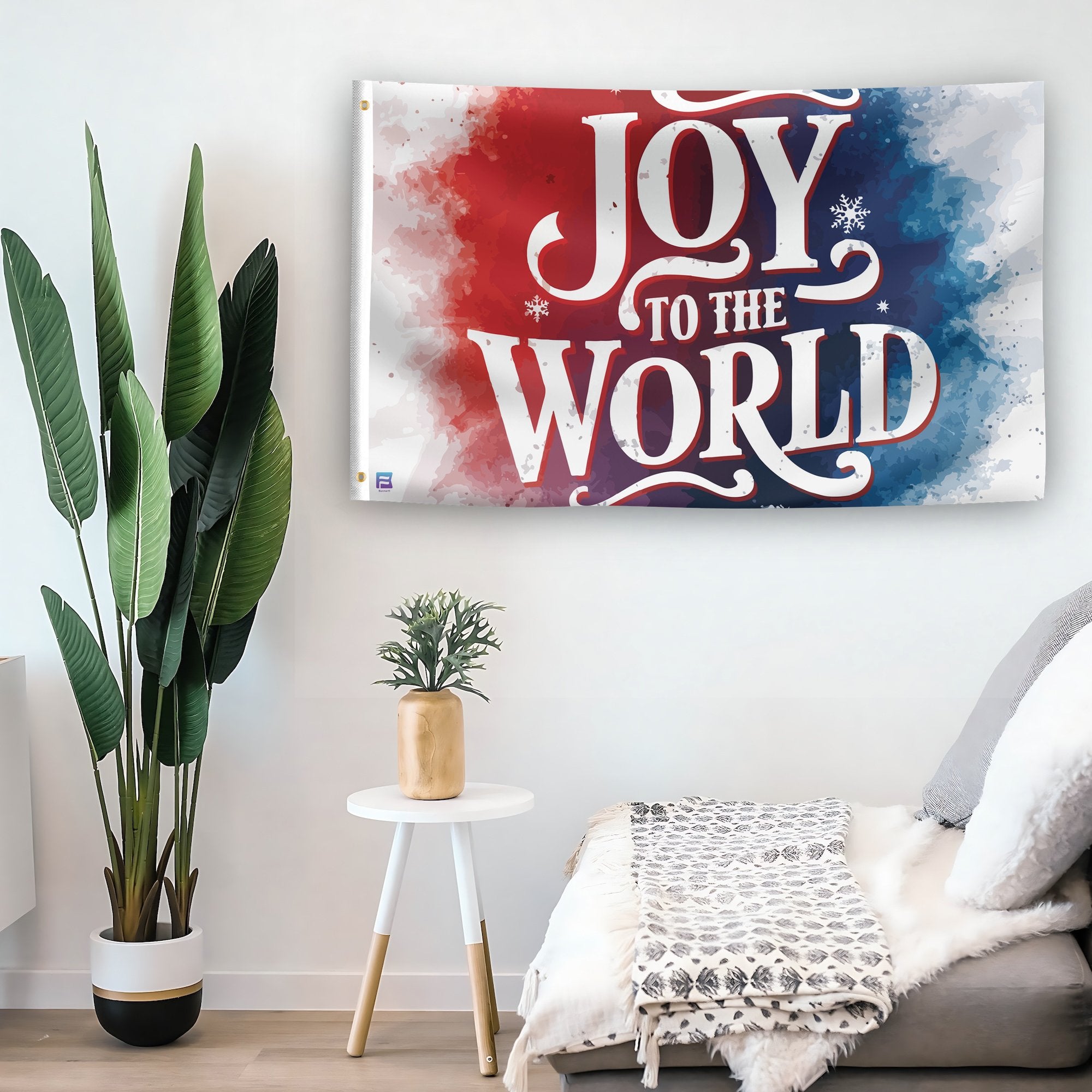 In a home setting, a flag with the saying "Joy To The World" is mounted on a white wall by a side table.