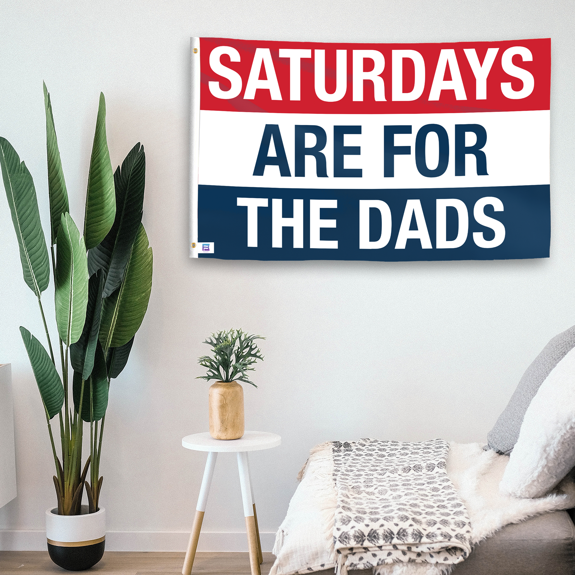 In a home setting, a flag with the saying "https://www.dropbox.com/scl/fi/015bcwidsqe7oysqvolx2/saturdays-are-for-the-dads_room.png?rlkey=hwj80ogywoouekd9t5n5yvb95&raw=1" is mounted on a white wall by a side table.