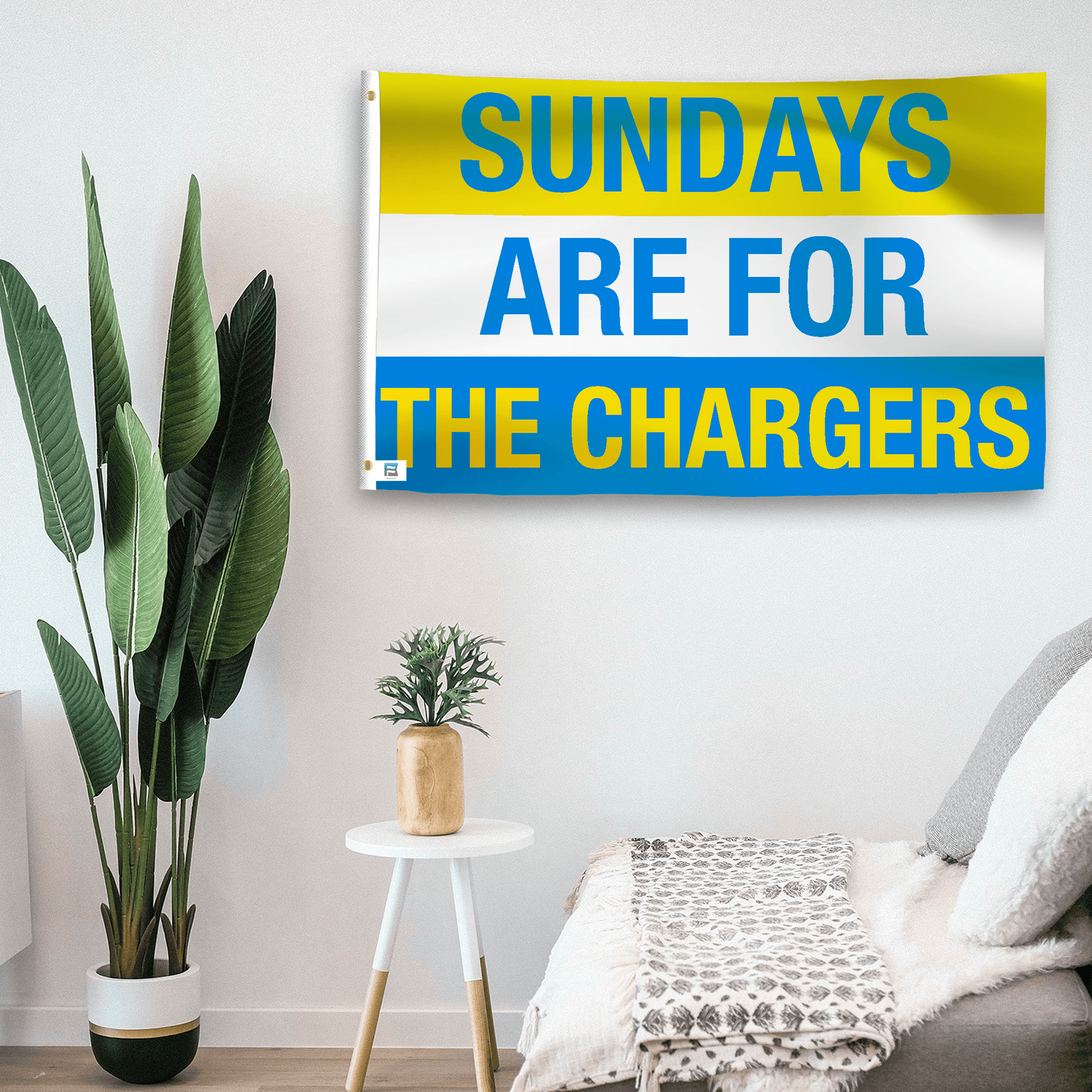 In a home setting, a flag with the saying "https://www.dropbox.com/scl/fi/9td4p5xmt501fz125brxp/sundays-are-for-the-chargers_room.png?rlkey=fhg7w5zf01u7u0pe6s0znfm7l&raw=1" is mounted on a white wall by a side table.