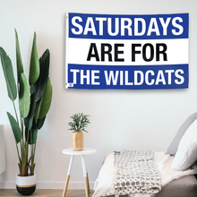 Load image into Gallery viewer, In a home setting, a flag with the saying &quot;Saturdays Are for the Wildcats Kentucky&quot; is mounted on a white wall by a side table.
