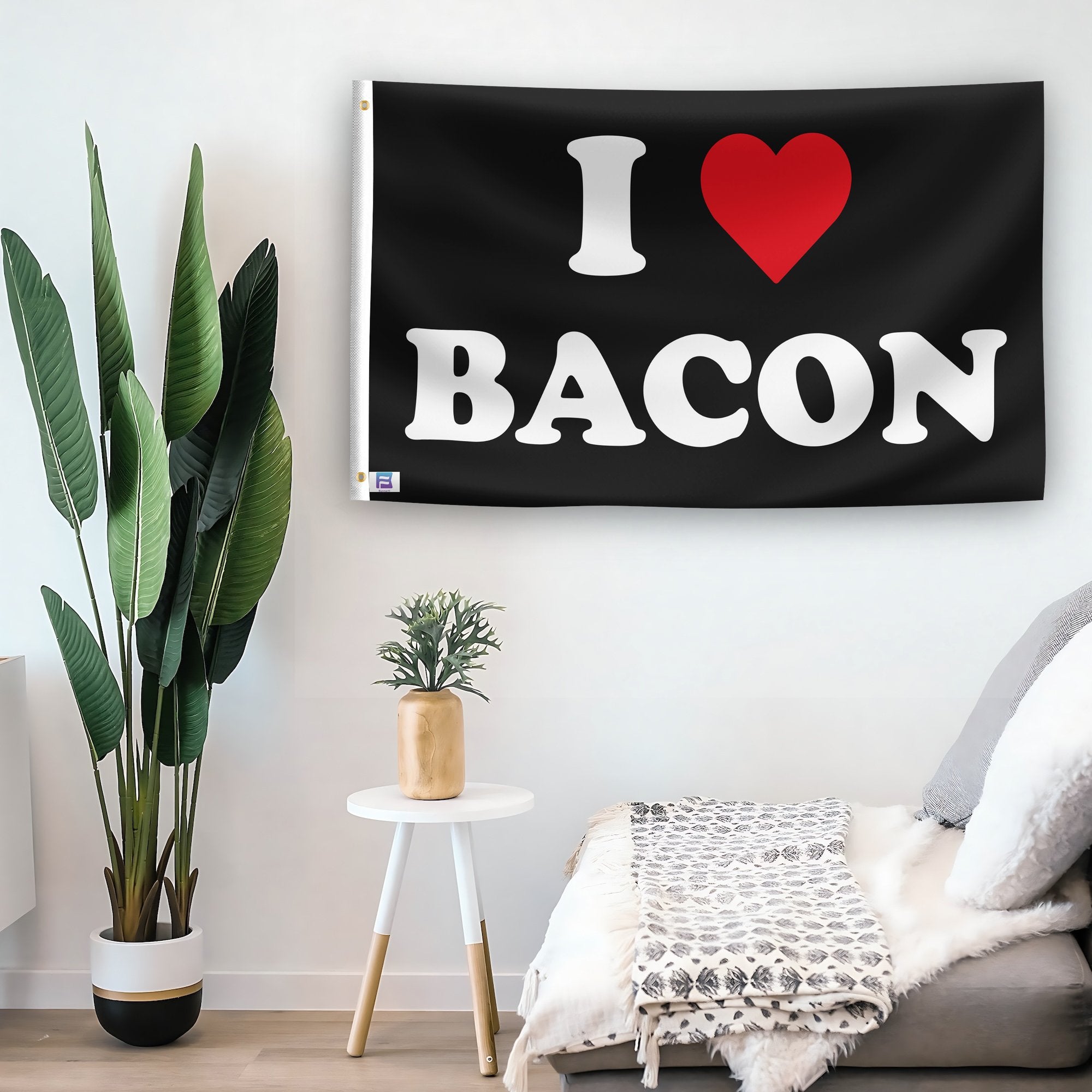 In a home setting, a flag with the saying "I Love Bacon" is mounted on a white wall by a side table.