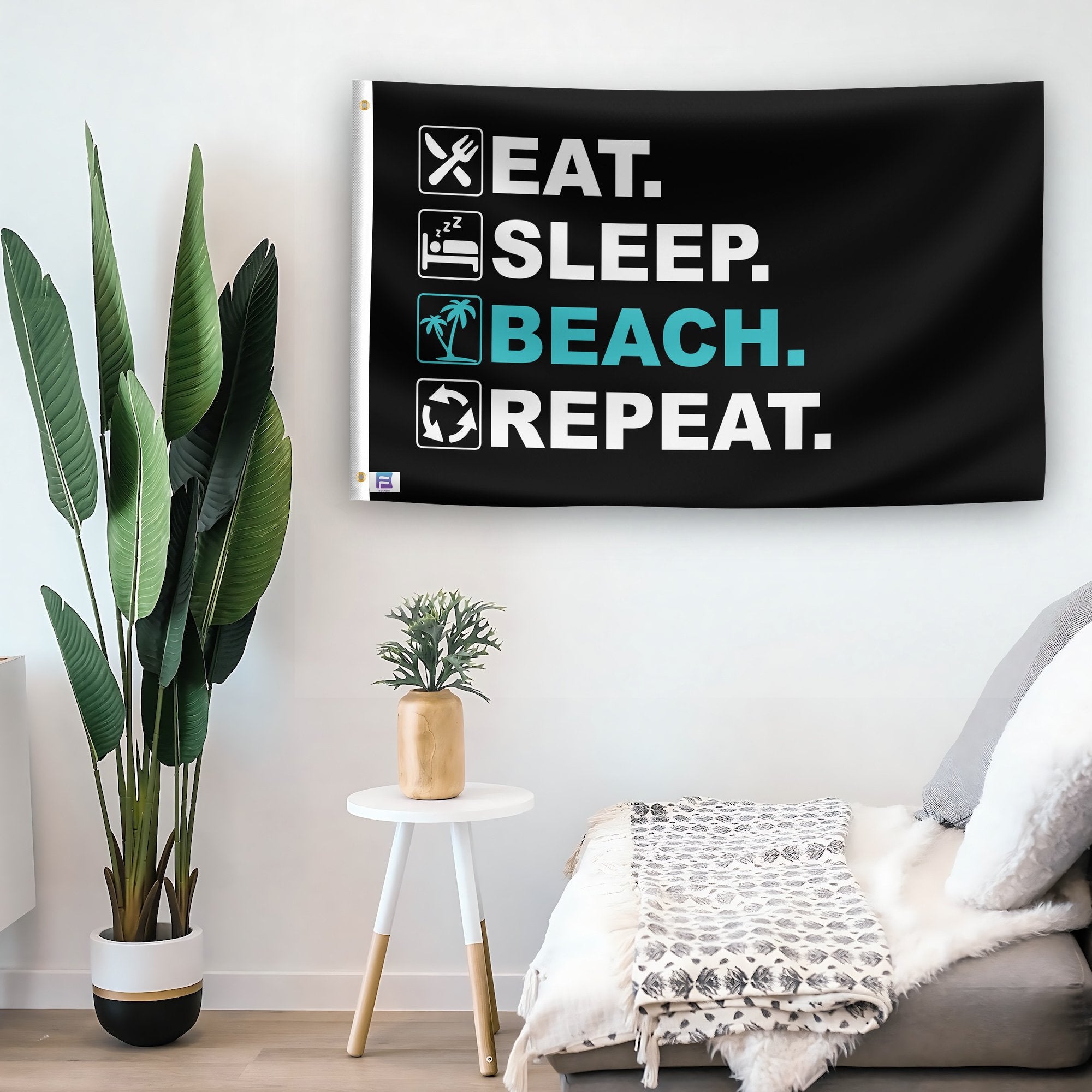 In a home setting, a flag with the saying "Eat Sleep Beach Repeat" is mounted on a white wall by a side table.