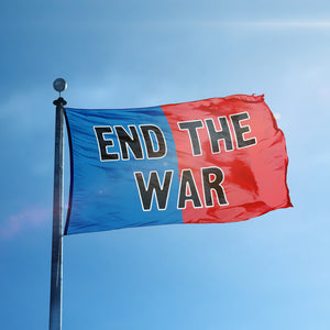 A flag containing a political slogan displayed on a high pole, featuring a patriotic red and blue background.