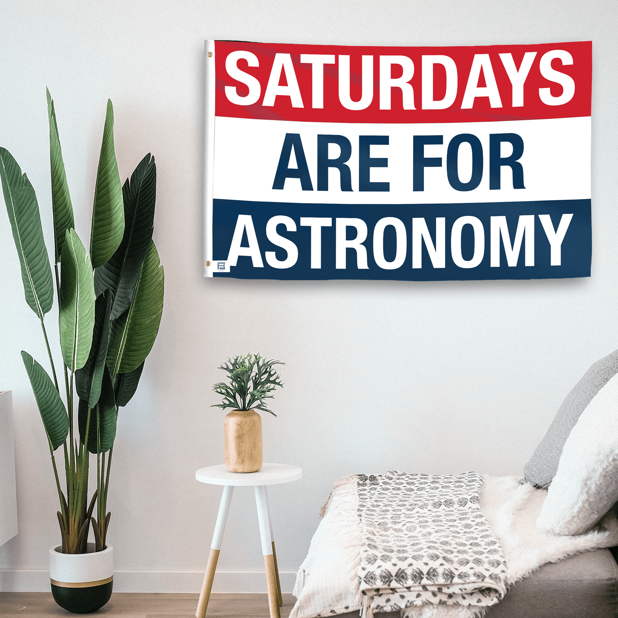 In a home setting, a flag with the saying "https://www.dropbox.com/scl/fi/tjszr3eox8oigg1sqovyt/saturdays-are-for-astronomy_room.png?rlkey=p04pa7m2ny6n54mny0d1ytz59&raw=1" is mounted on a white wall by a side table.