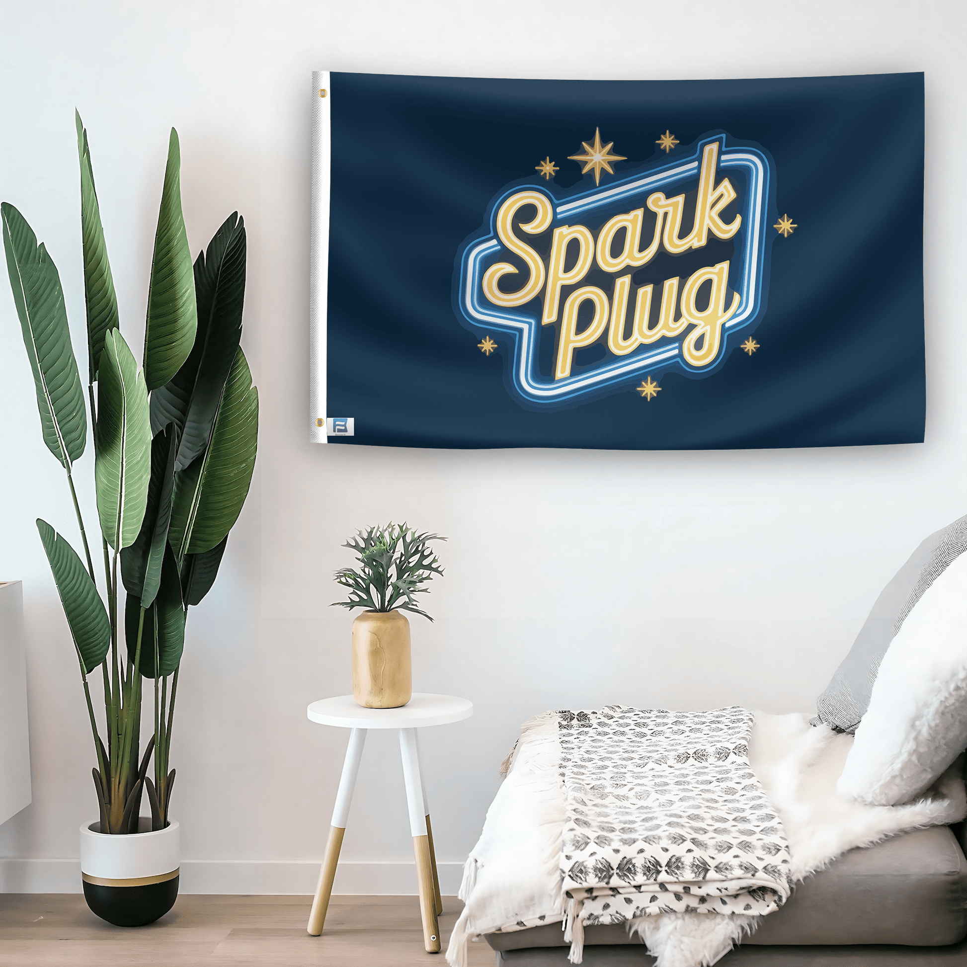 In a home setting, a flag with the saying "Spark Plug" is mounted on a white wall by a side table.