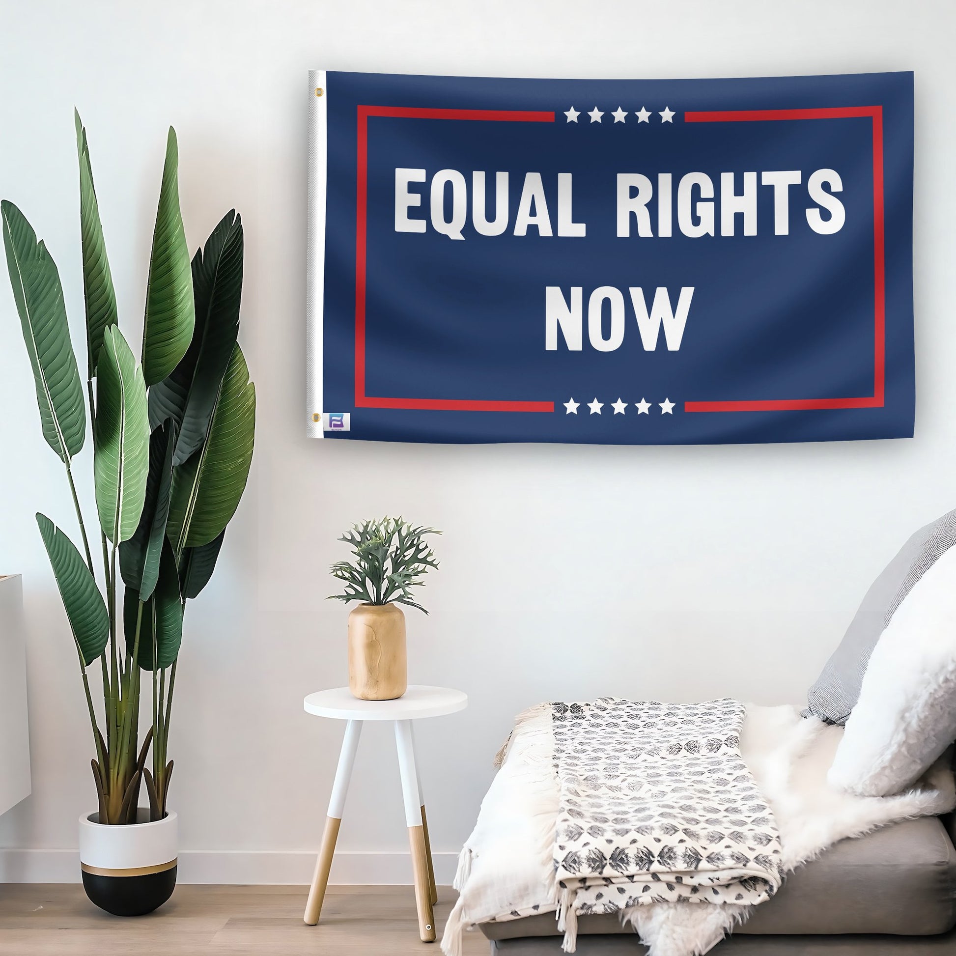 In a home setting, a flag with the saying "Equal Rights Now Political" is mounted on a white wall by a side table.