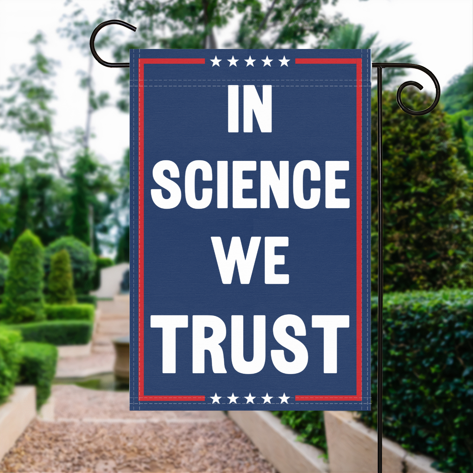 A red, white and blue political garden flag with the slogan In Science We Trust.