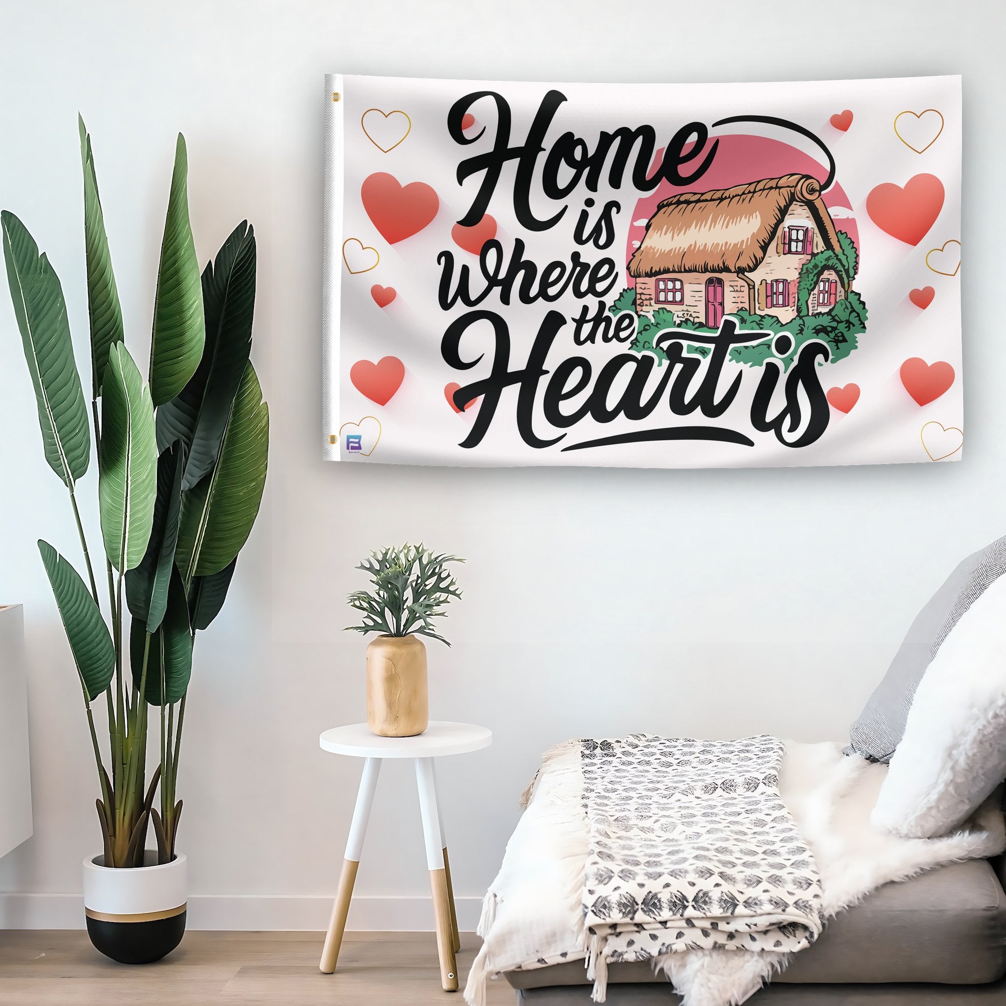 In a home setting, a flag with the saying "Home Is Where The Heart Is" is mounted on a white wall by a side table.