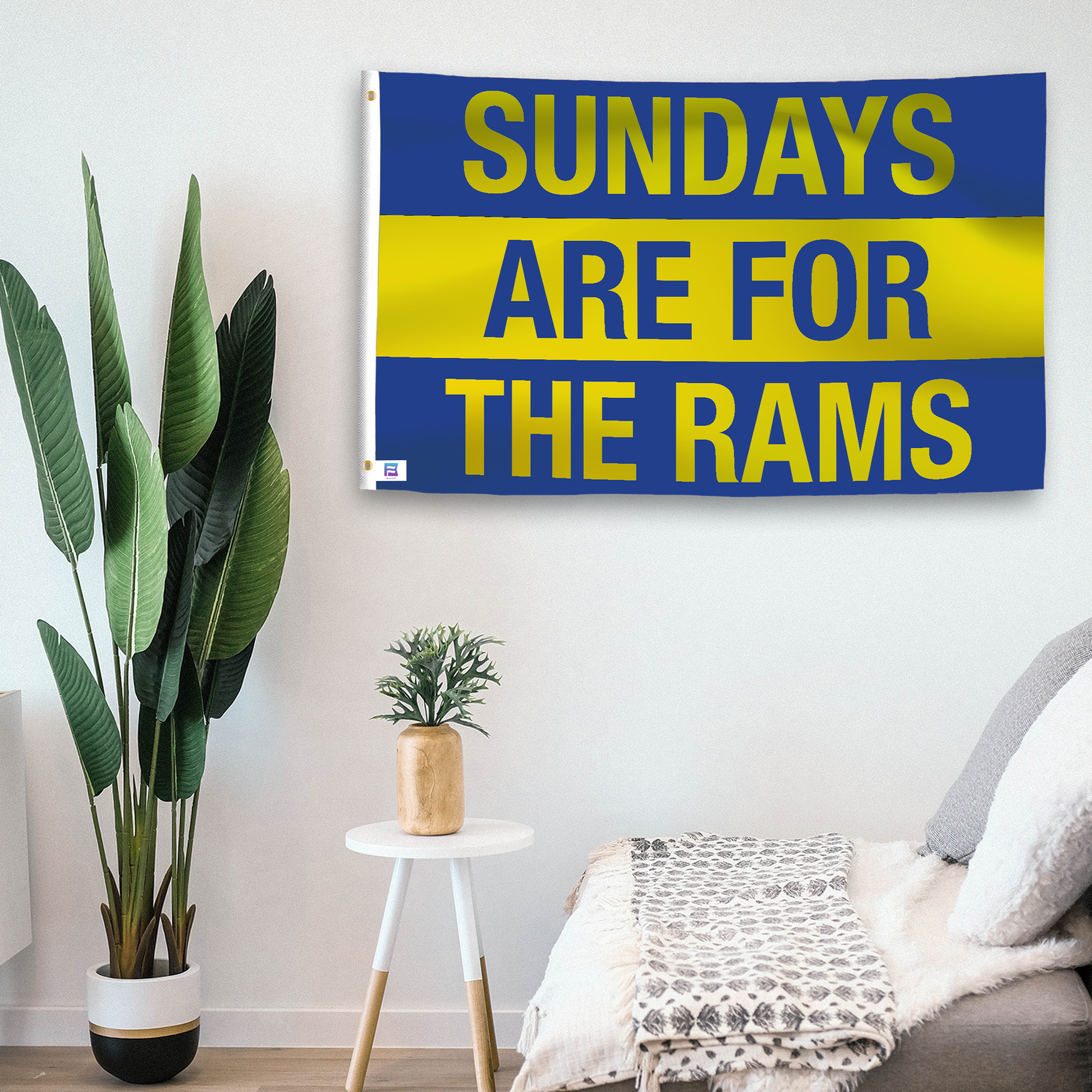 In a home setting, a flag with the saying "https://www.dropbox.com/scl/fi/ntqfvb2ylmly6z4g1fz5o/sundays-are-for-the-rams_room.png?rlkey=ok4xkstf2yg2wxb7khfnnqa04&raw=1" is mounted on a white wall by a side table.