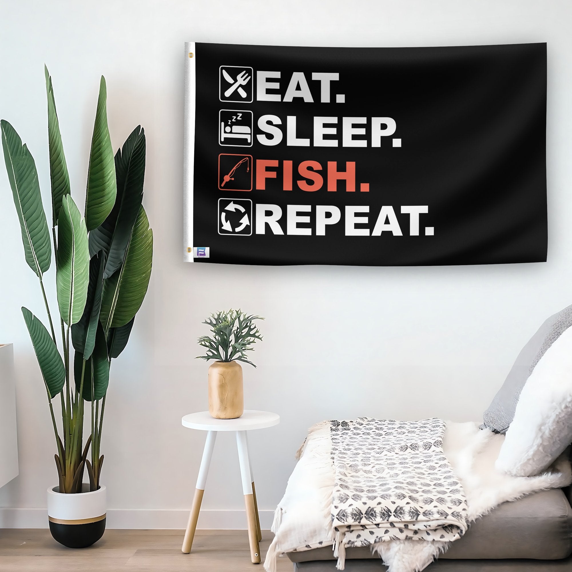 In a home setting, a flag with the saying "Eat Sleep Fish Repeat" is mounted on a white wall by a side table.