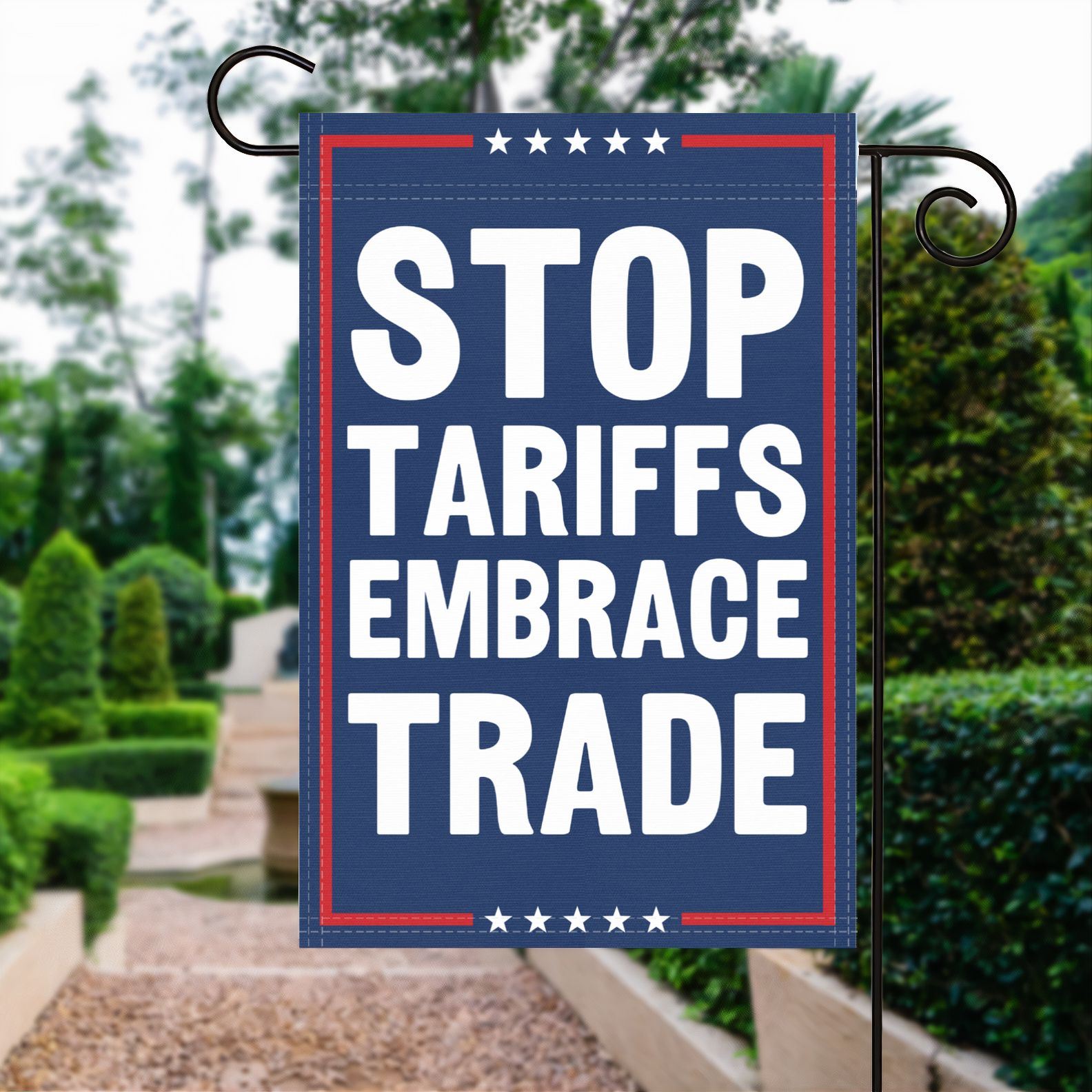 A red, white and blue political garden flag with the slogan Stop Tariffs Embrace Trade.