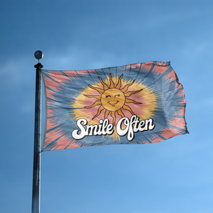 A flag with the saying "Smile Often 70s Style" displayed on a high pole, with a tie dye style color scheme.