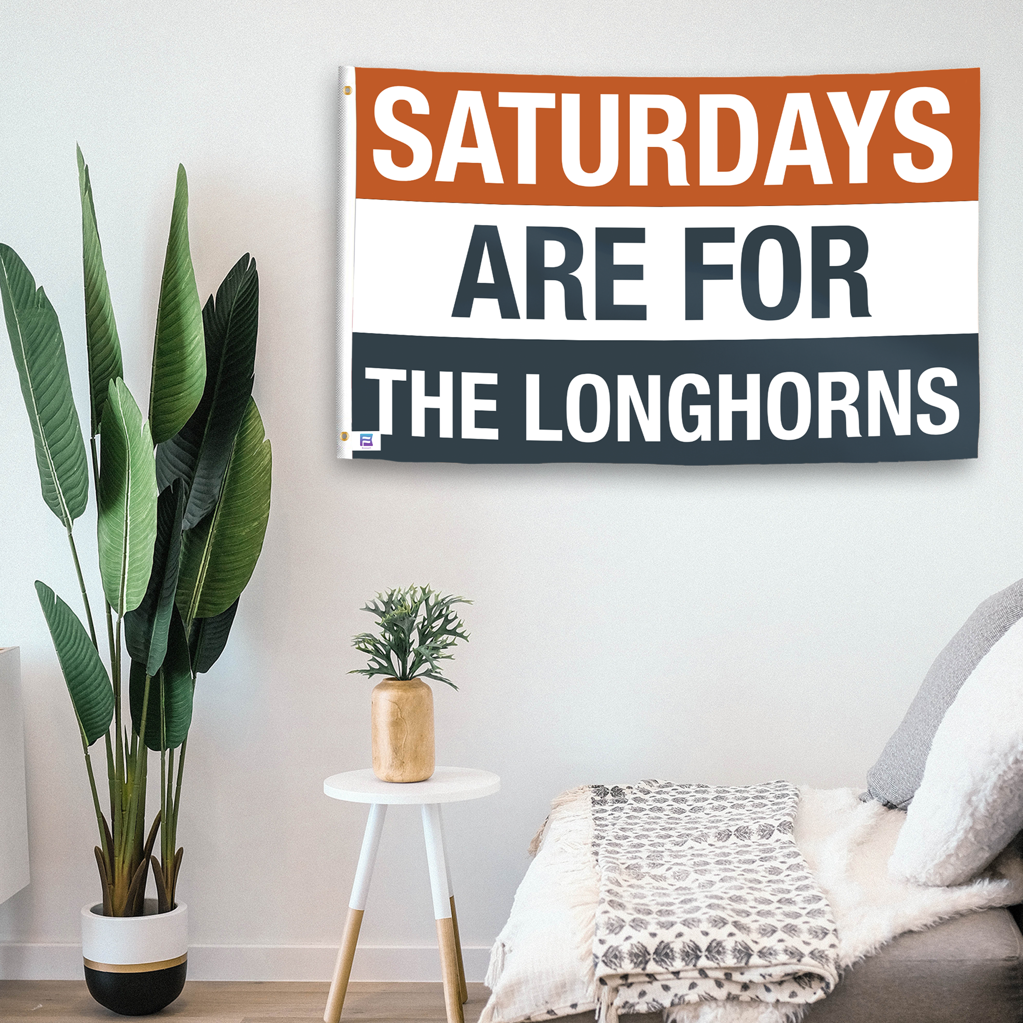 In a home setting, a flag with the saying "Saturdays Are for the Longhorns" is mounted on a white wall by a side table.