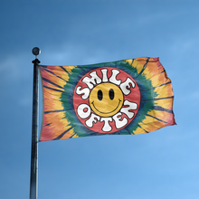 Load image into Gallery viewer, A flag with the saying &quot;Smile Often&quot; displayed on a high pole, with a tie dye style color scheme.
