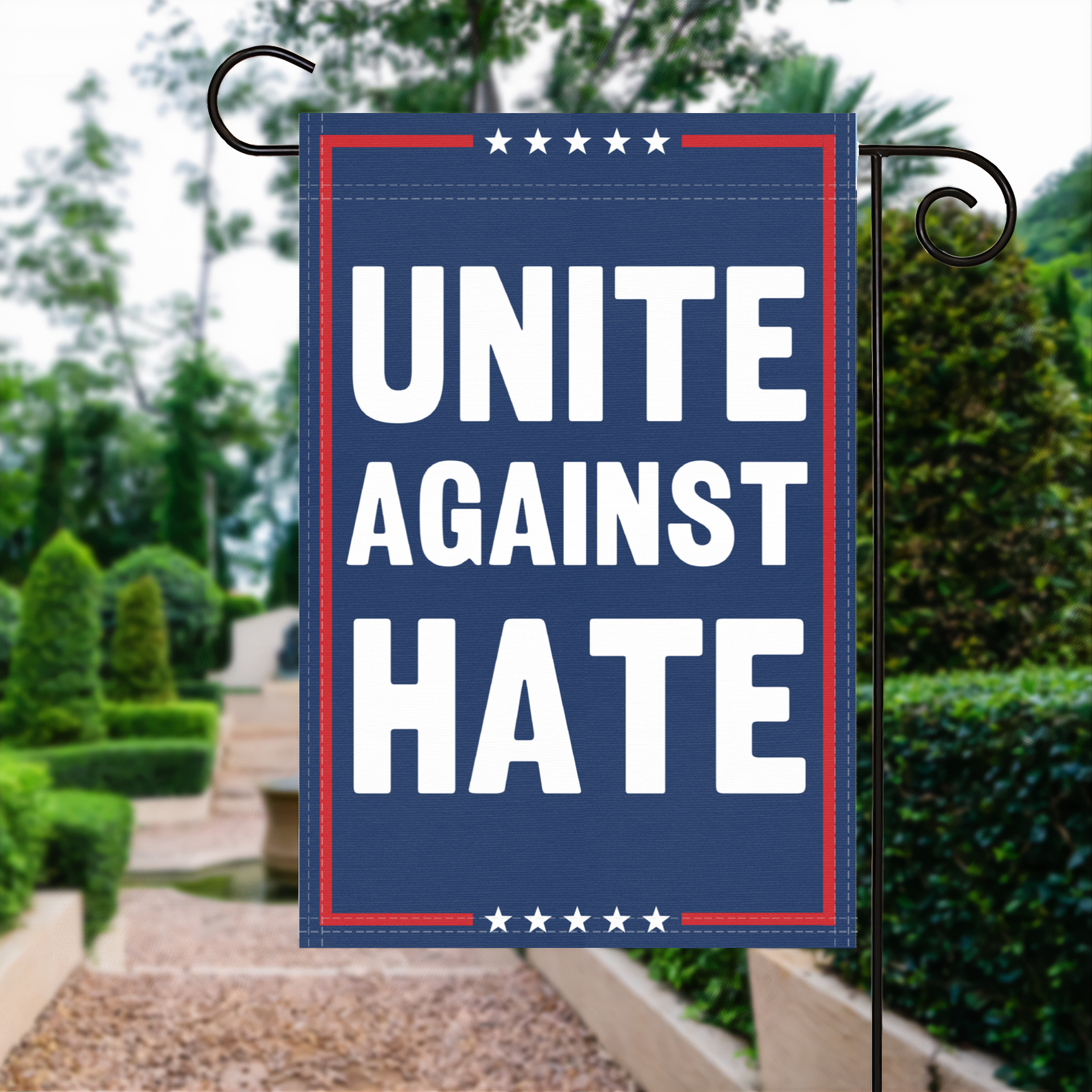 A red, white and blue political garden flag with the slogan Unite Against Hate.