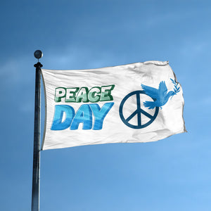 A flag with the saying "Peace Day" displayed on a high pole, with a holiday themed color scheme.