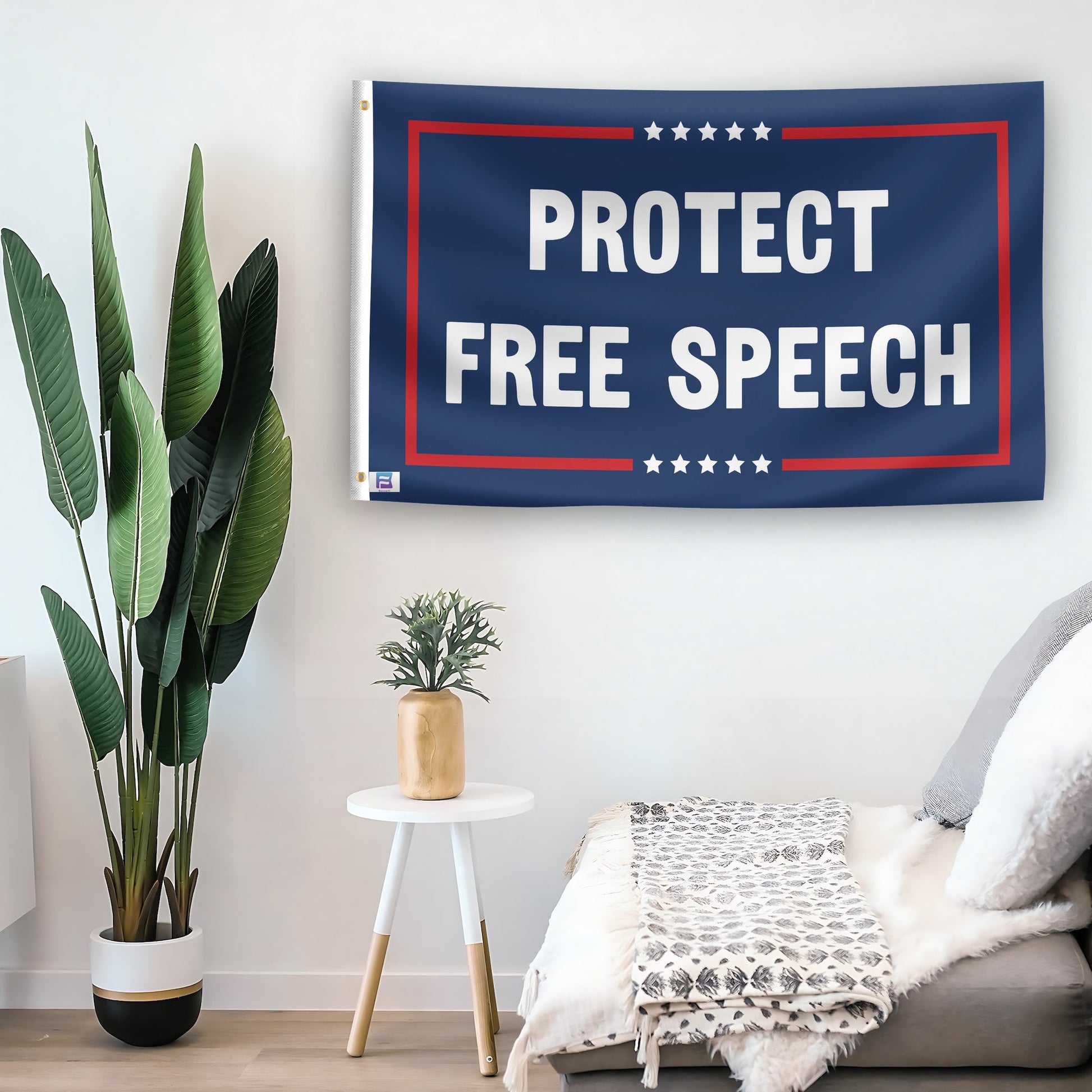 In a home setting, a flag with the saying "Protect Free Speech Political" is mounted on a white wall by a side table.