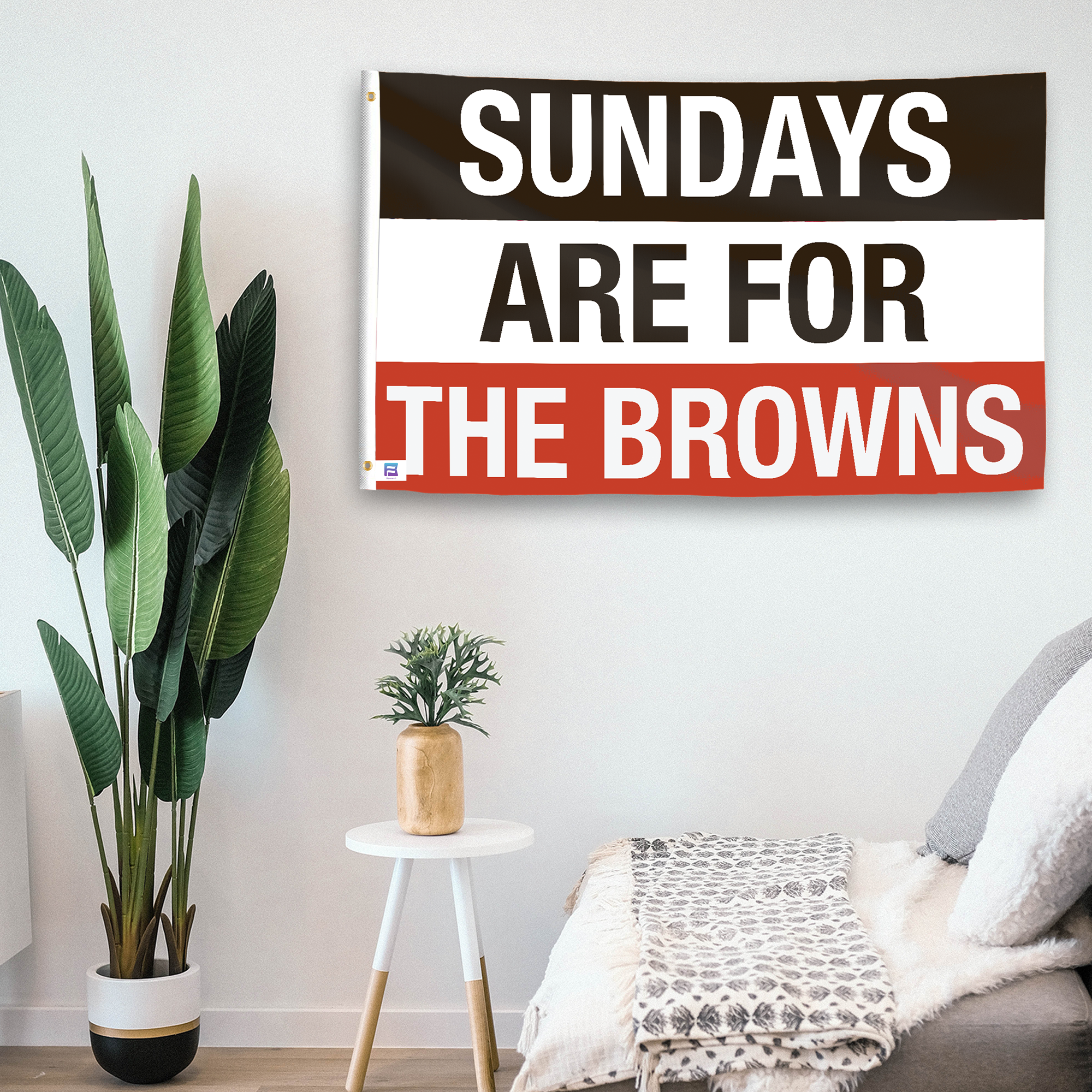 In a home setting, a flag with the saying "https://www.dropbox.com/scl/fi/efn42oqqryvfwr10elpea/sundays-are-for-the-browns_room.png?rlkey=3mvakp7vfk3lc5mzgqlgckgp2&raw=1" is mounted on a white wall by a side table.