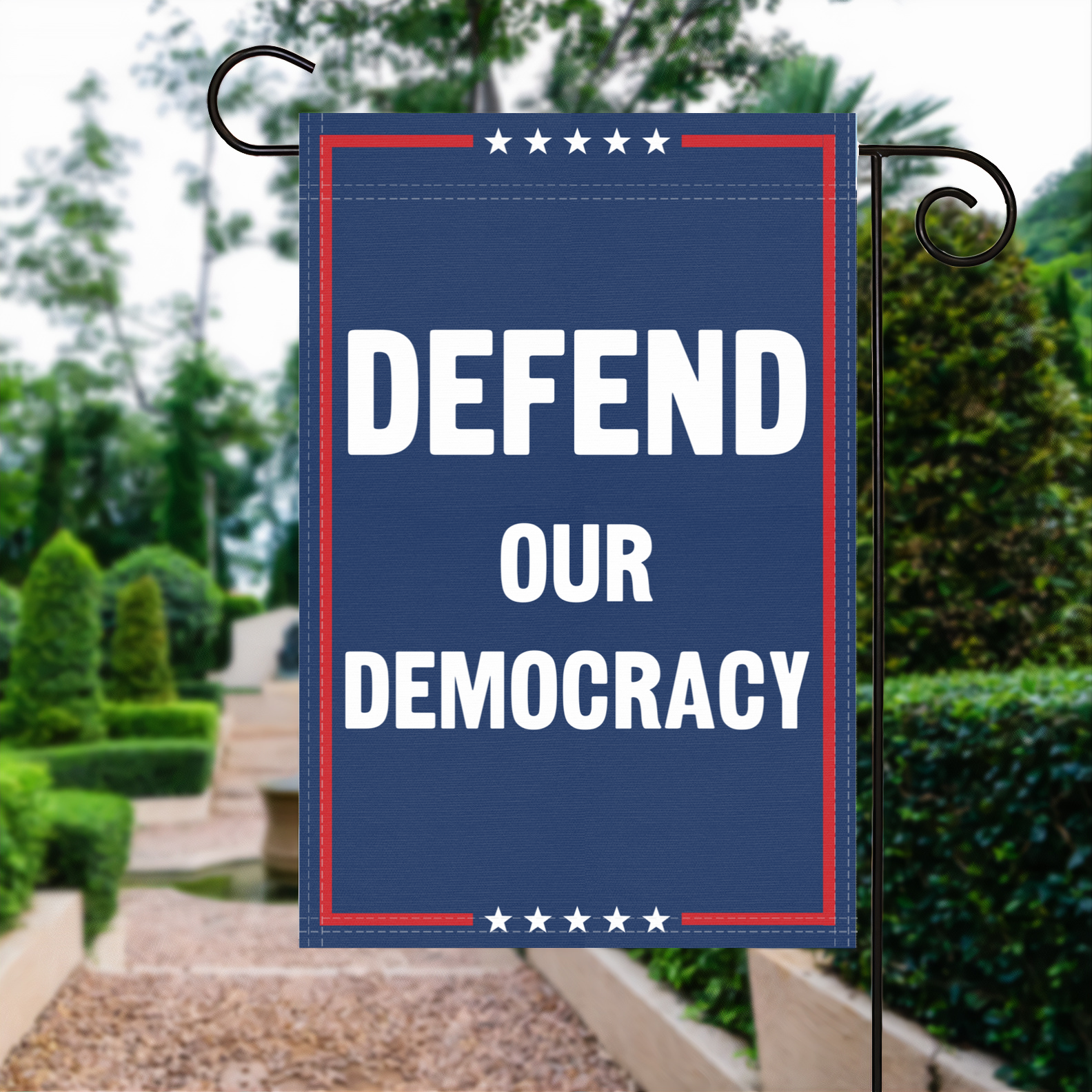 A red, white and blue political garden flag with the slogan Defend Our Democracy.