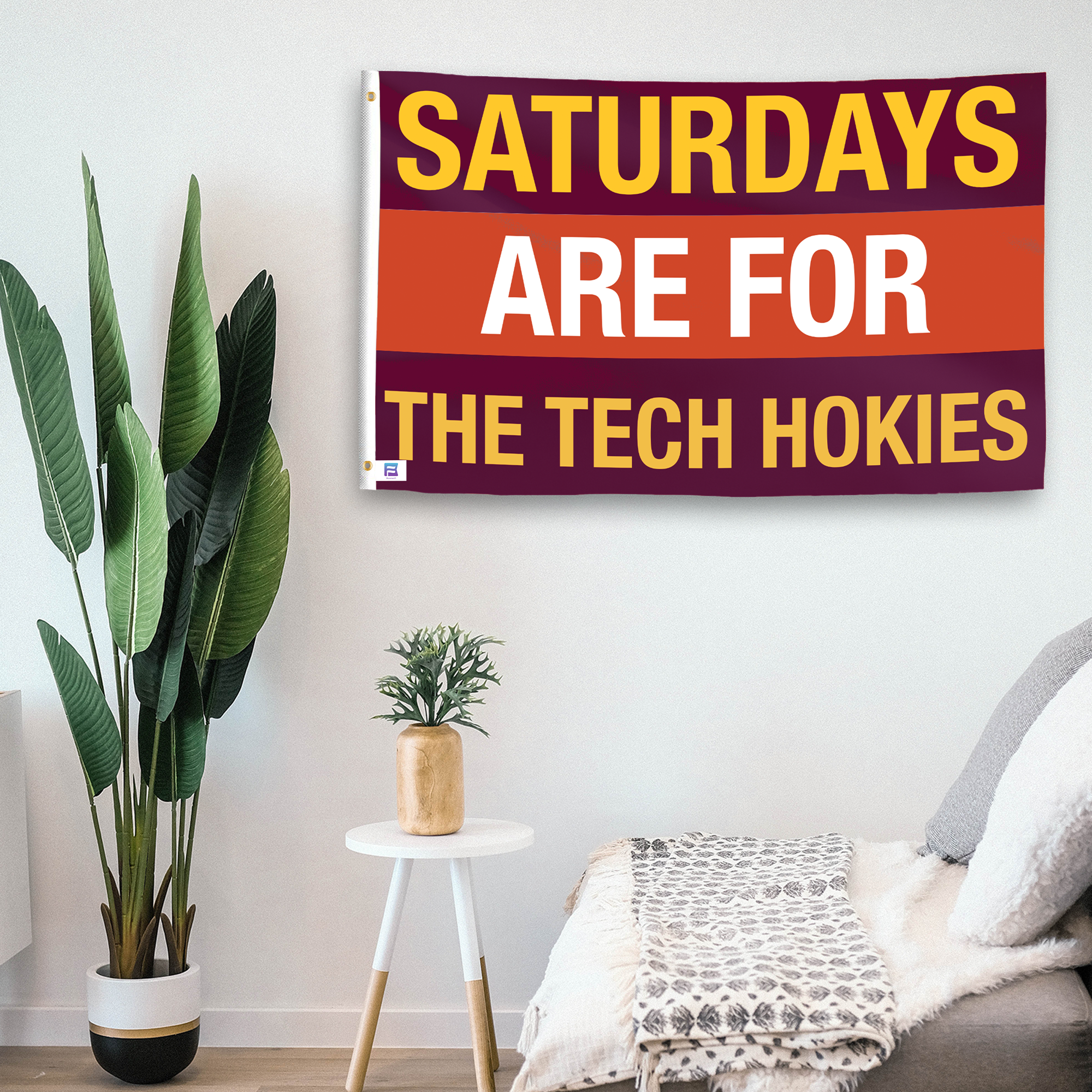 In a home setting, a flag with the saying "Saturdays Are for the Tech Hokies" is mounted on a white wall by a side table.