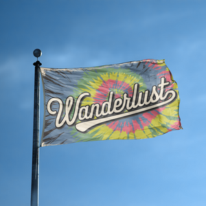 A flag with the saying "Wanderlust" displayed on a high pole, with a tie dye style color scheme.