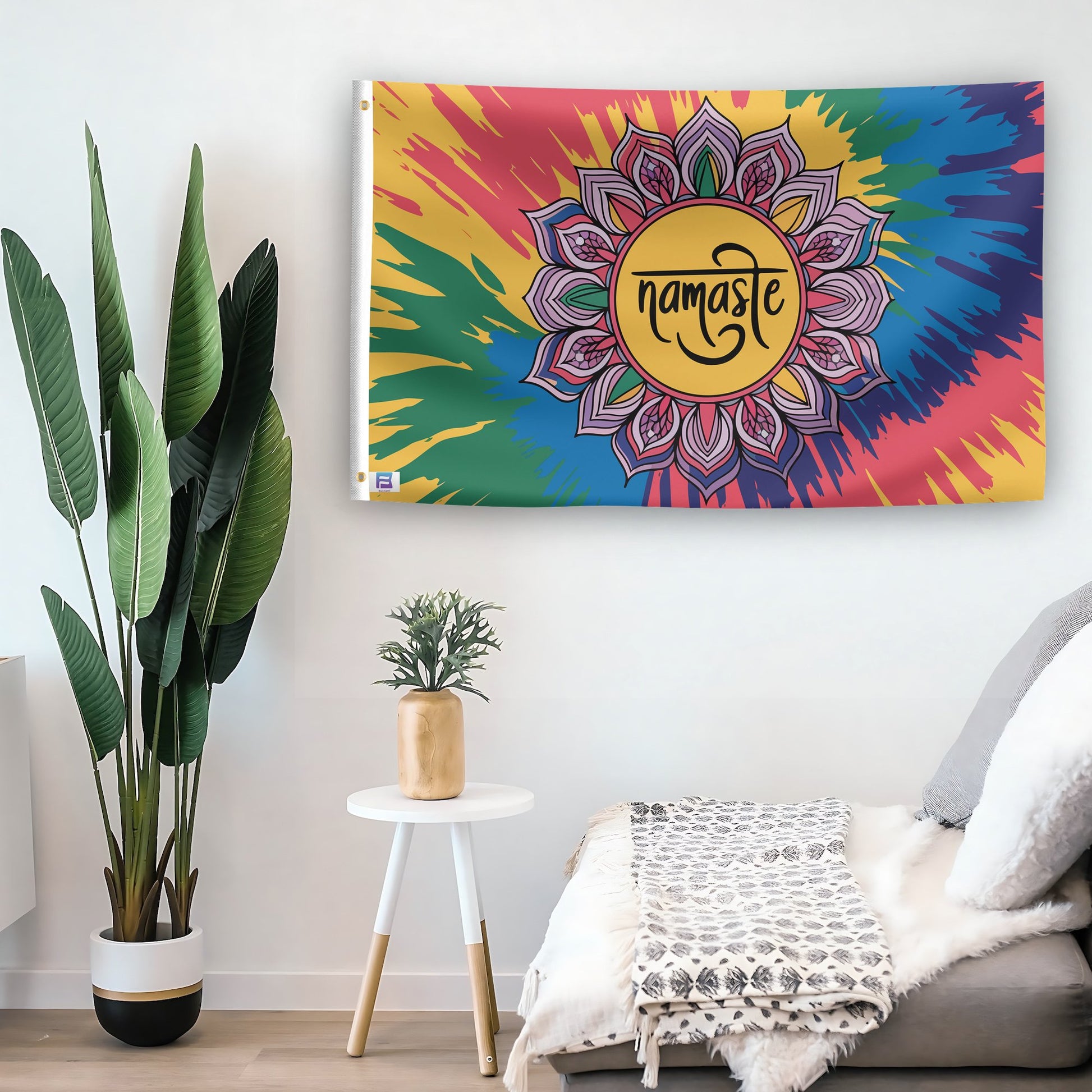 In a home setting, a flag with the saying "Namaste" is mounted on a white wall by a side table.