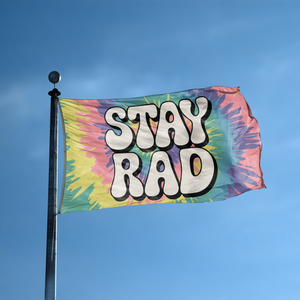 A flag with the saying "Stay Rad" displayed on a high pole, with a tie dye style color scheme.