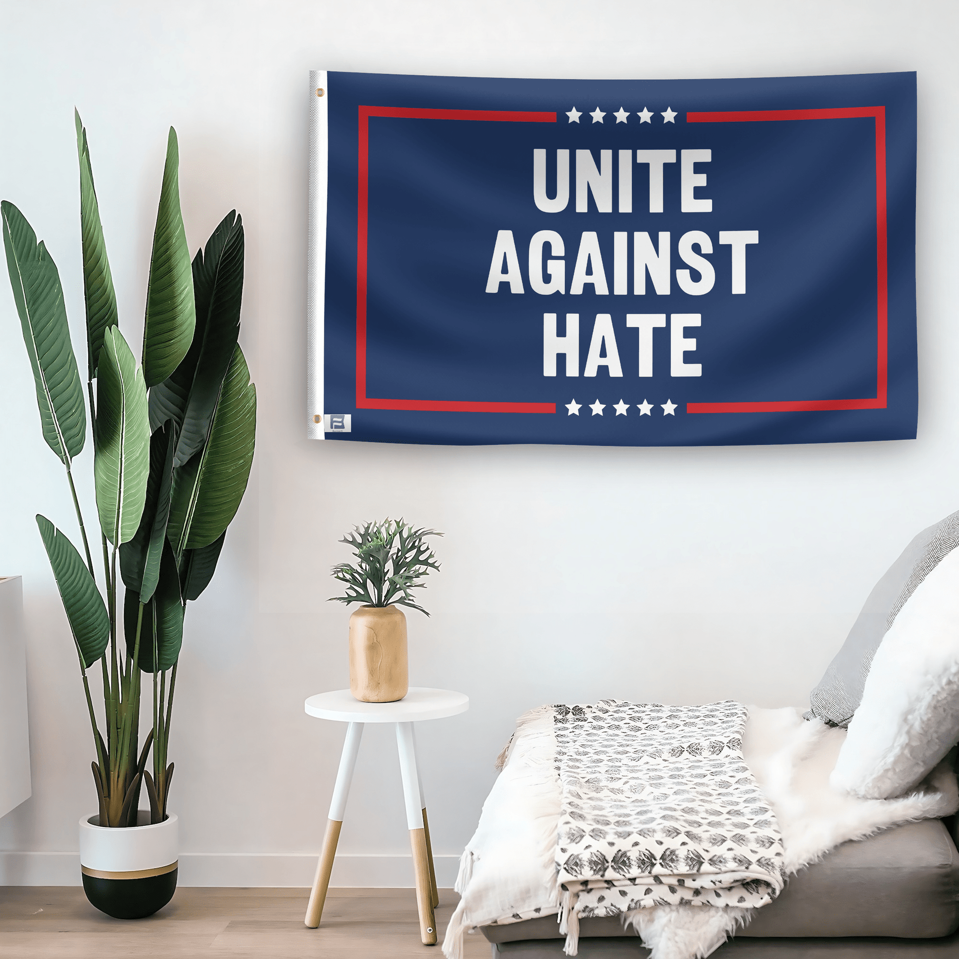 In a home setting, a flag with the saying "Unite Against Hate Political" is mounted on a white wall by a side table.