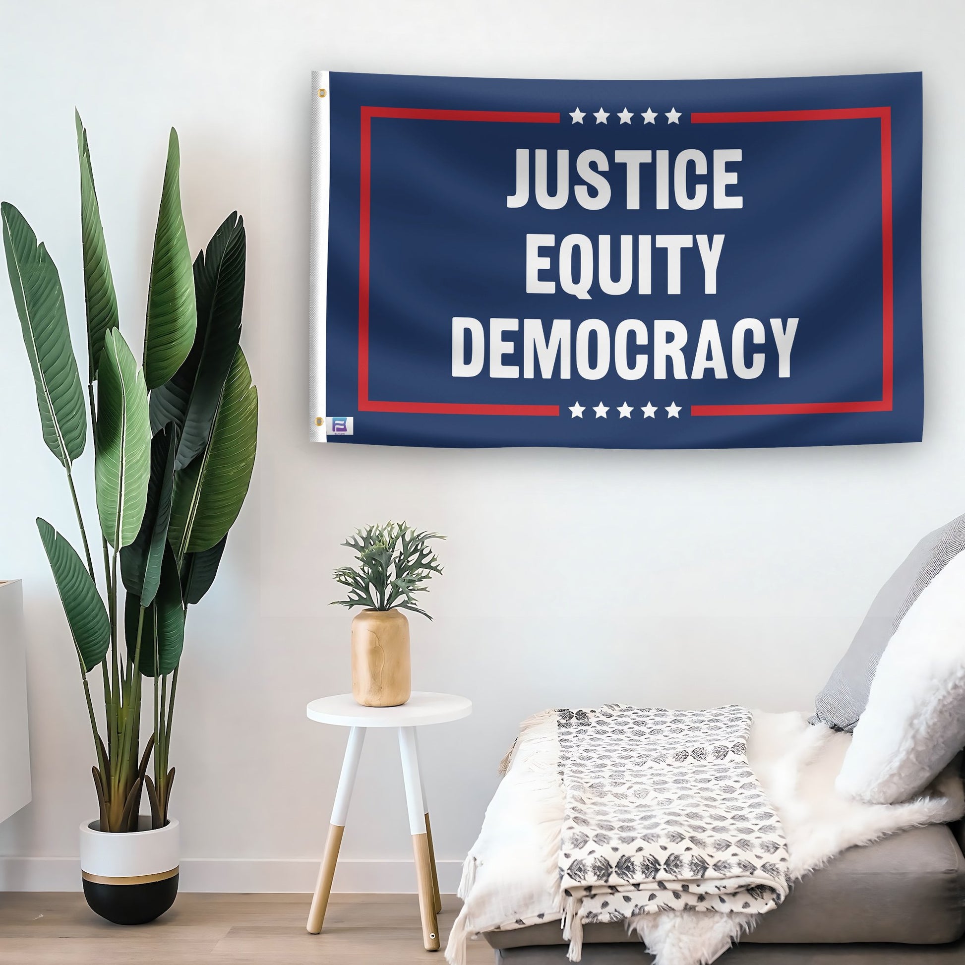 In a home setting, a flag with the saying "Justice Equity Democracy Political" is mounted on a white wall by a side table.